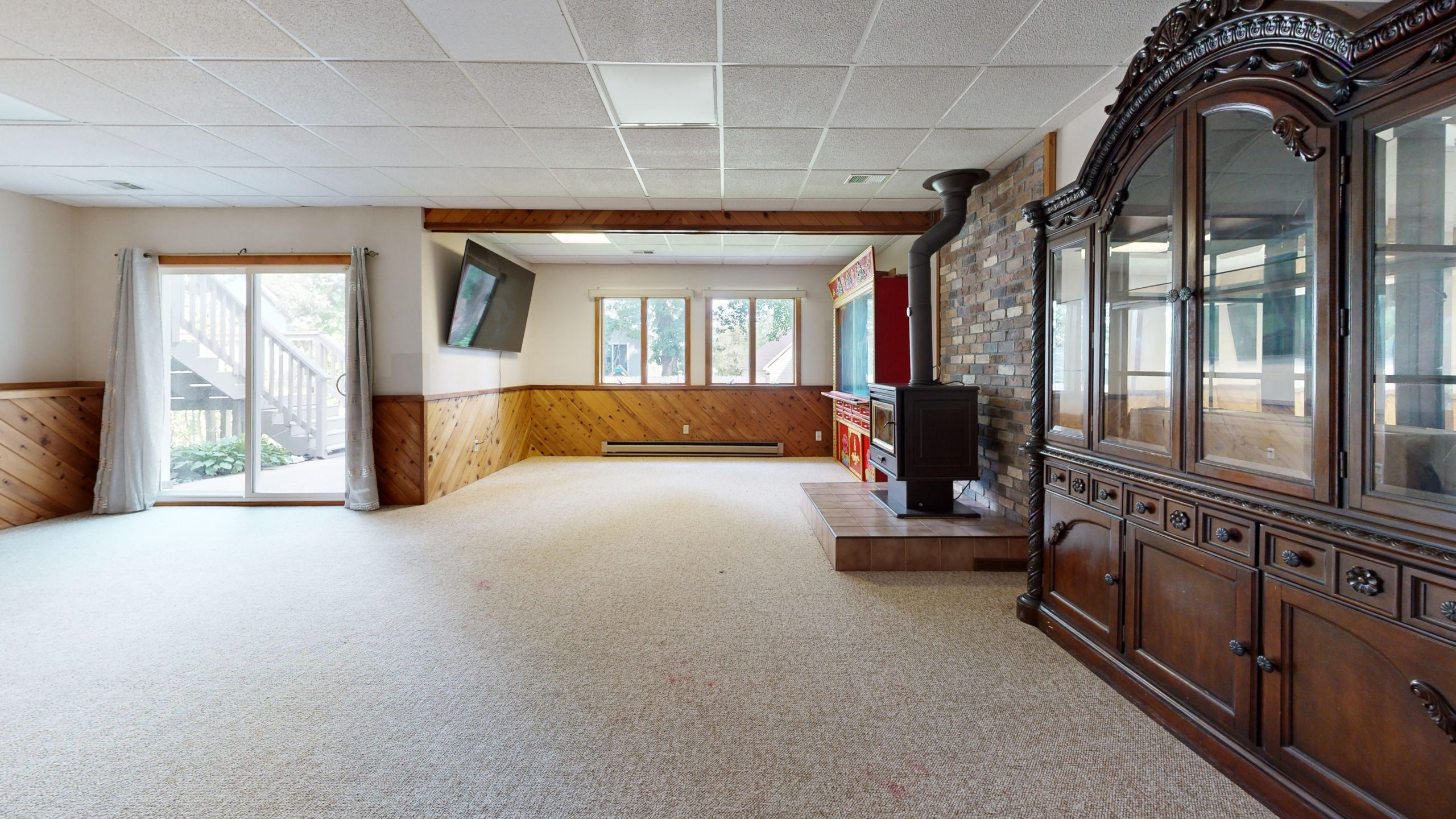 Cozy basement with wooden paneling, fireplace, and sunny windows. Great for relaxation.