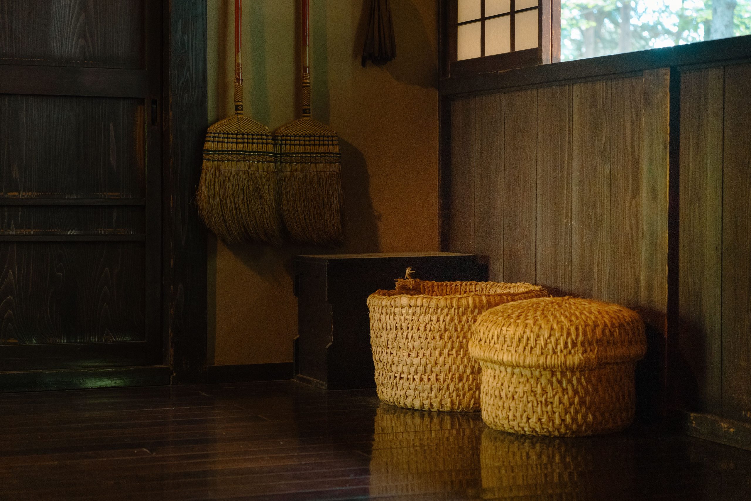Cozy Japanese room featuring woven baskets and traditional brooms in dim lighting.