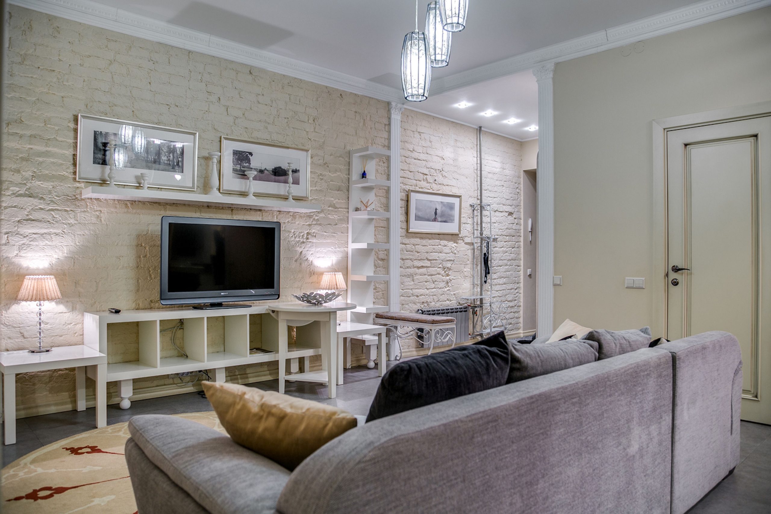 Cozy modern living room featuring a TV, brick walls, and stylish decor.