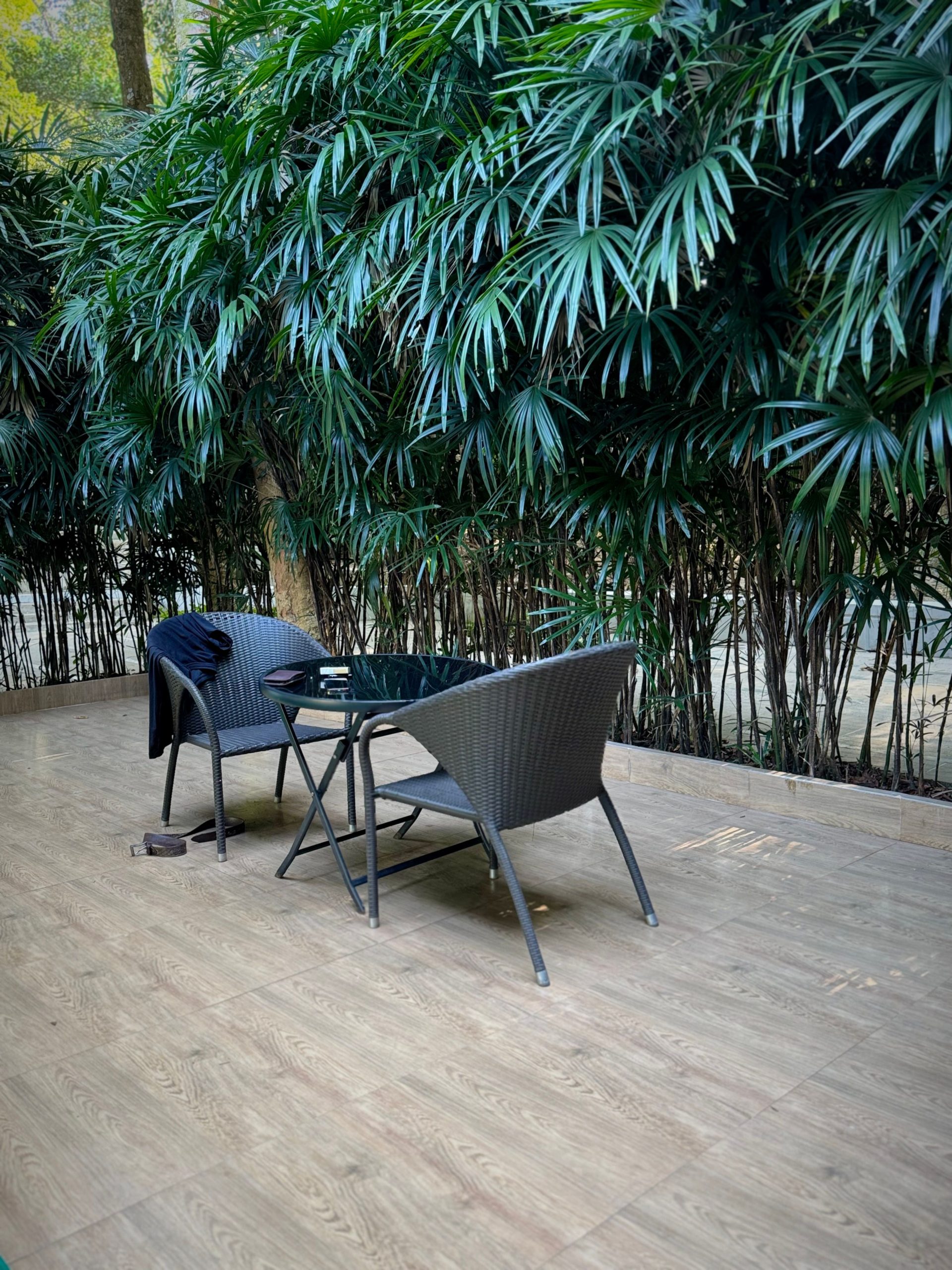Cozy outdoor patio with wicker chairs, wooden flooring, and lush foliage creating a serene atmosphere.