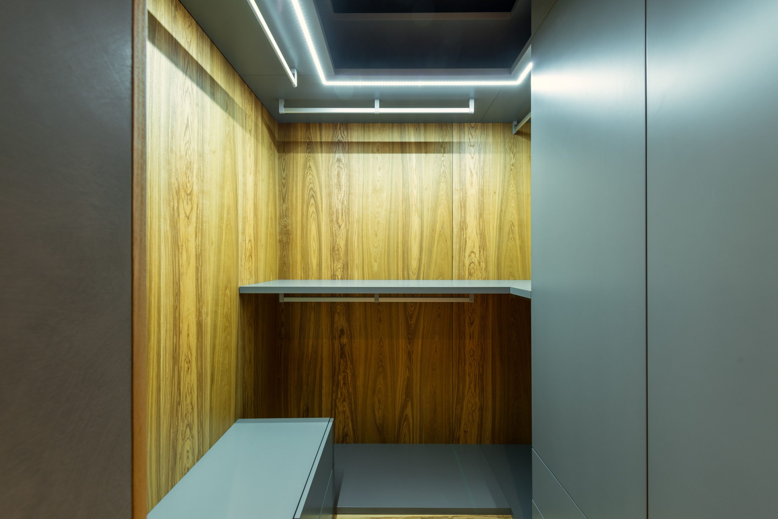 Creative design of empty wardrobe with shelf between racks illuminated by lamp at home