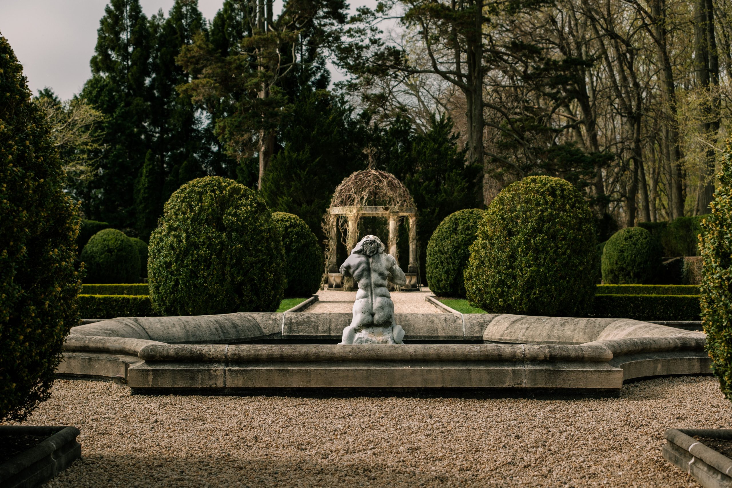 Elegant garden featuring a stone fountain, gazebo, and lush greenery in a tranquil setting.