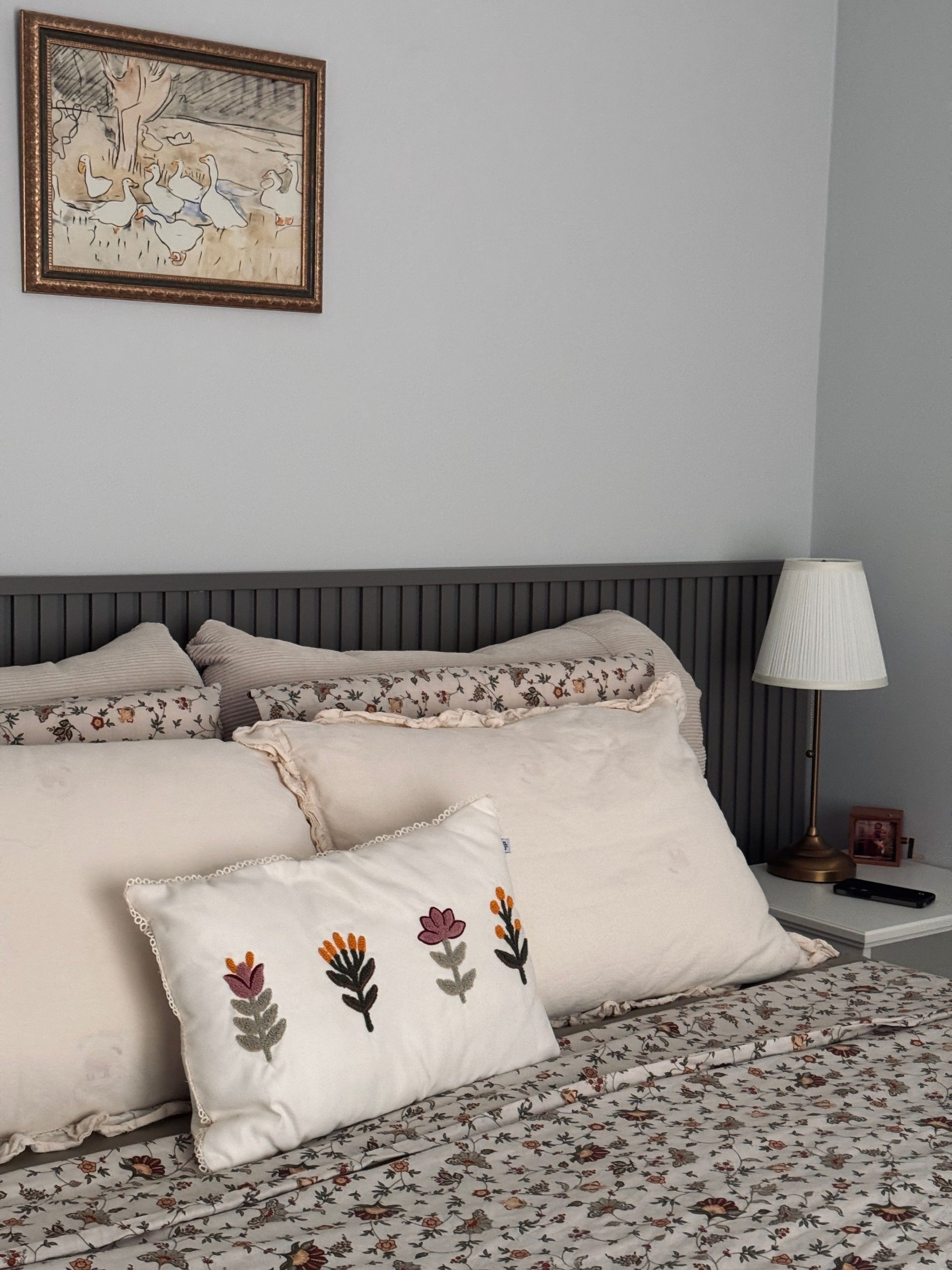 Inviting bedroom with floral bedding, decorative pillows, and framed wall art.