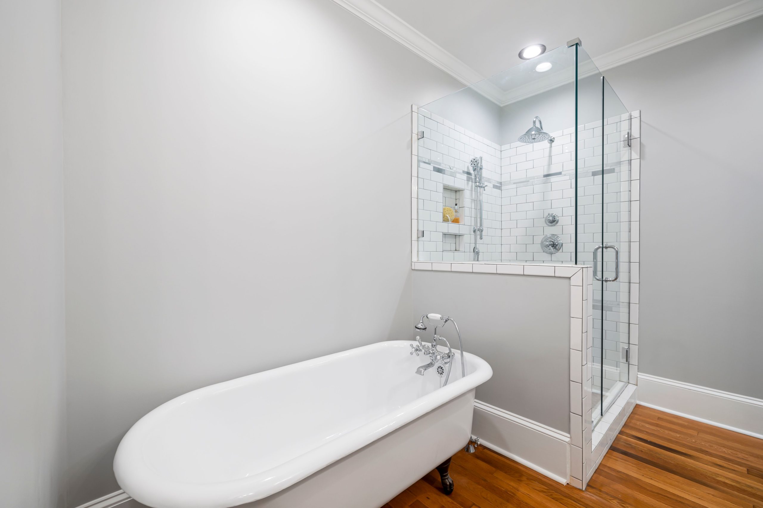 Modern minimalist bathroom featuring a luxurious clawfoot bathtub and a sleek glass-enclosed shower.