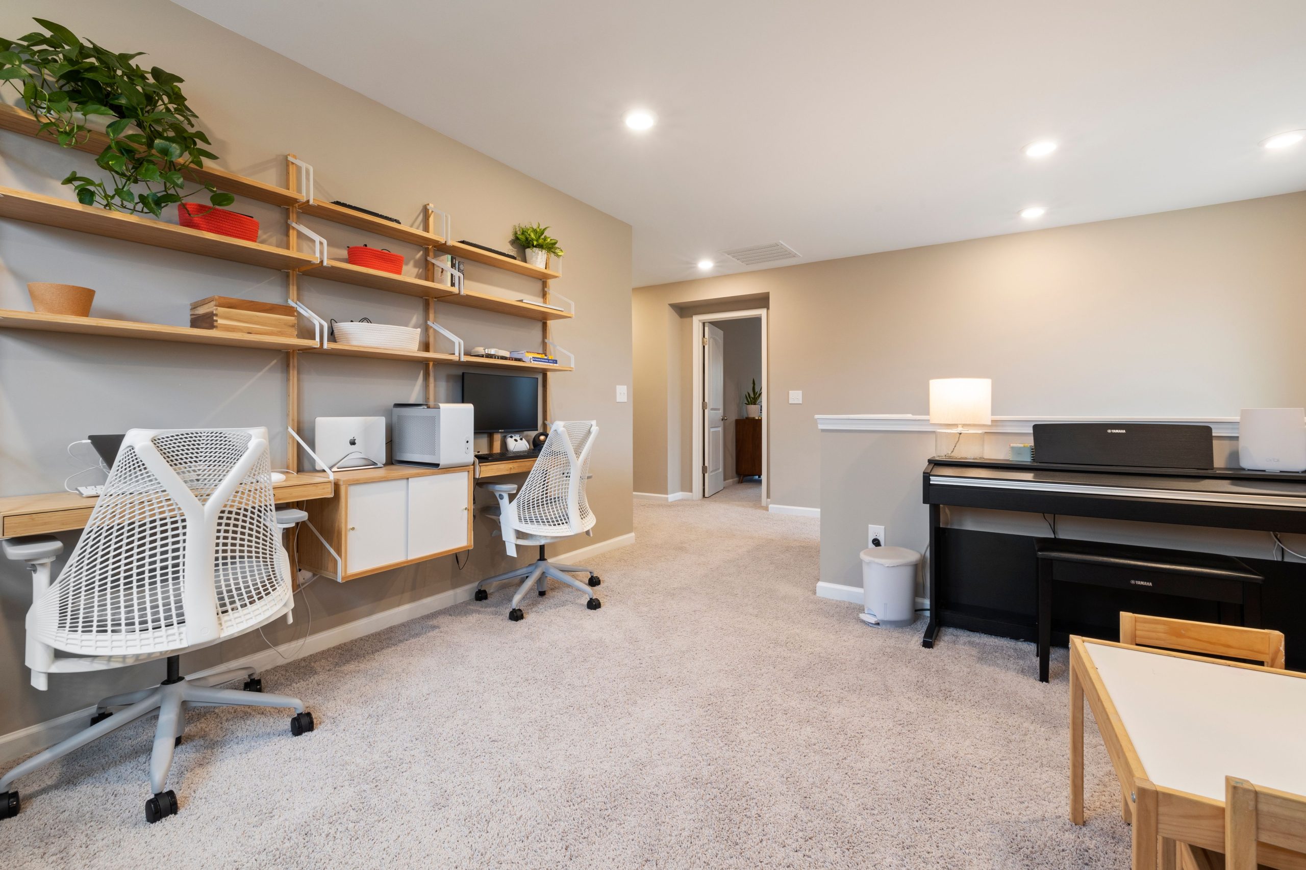 Spacious home office with contemporary design, showcasing workspace, shelves, and digital piano.