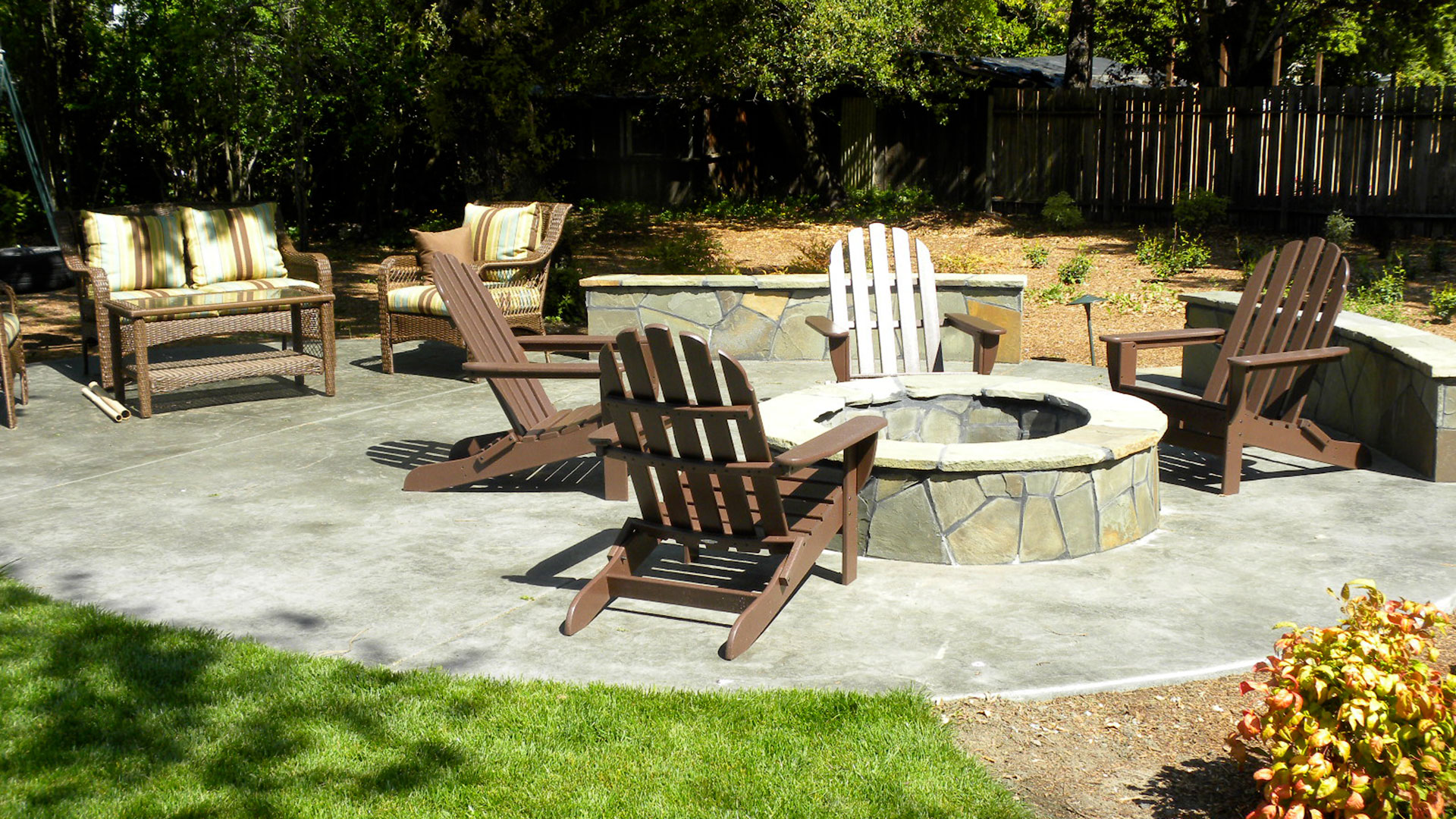 Stamped concrete patio featuring flagstone seat wall and fire pit - Details Landscape Art