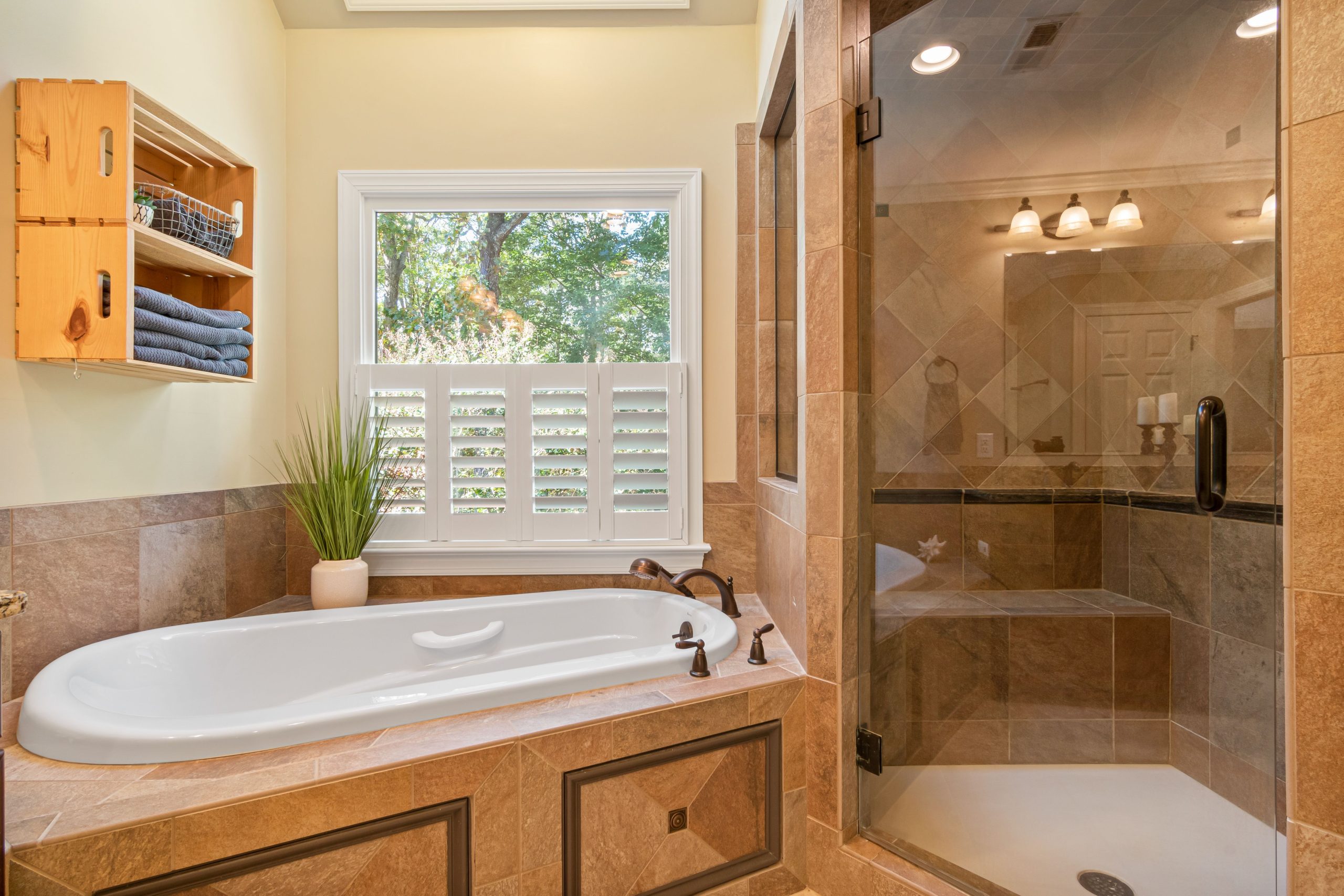 Stylish bathroom featuring a bathtub, shower, and natural lighting through large window.