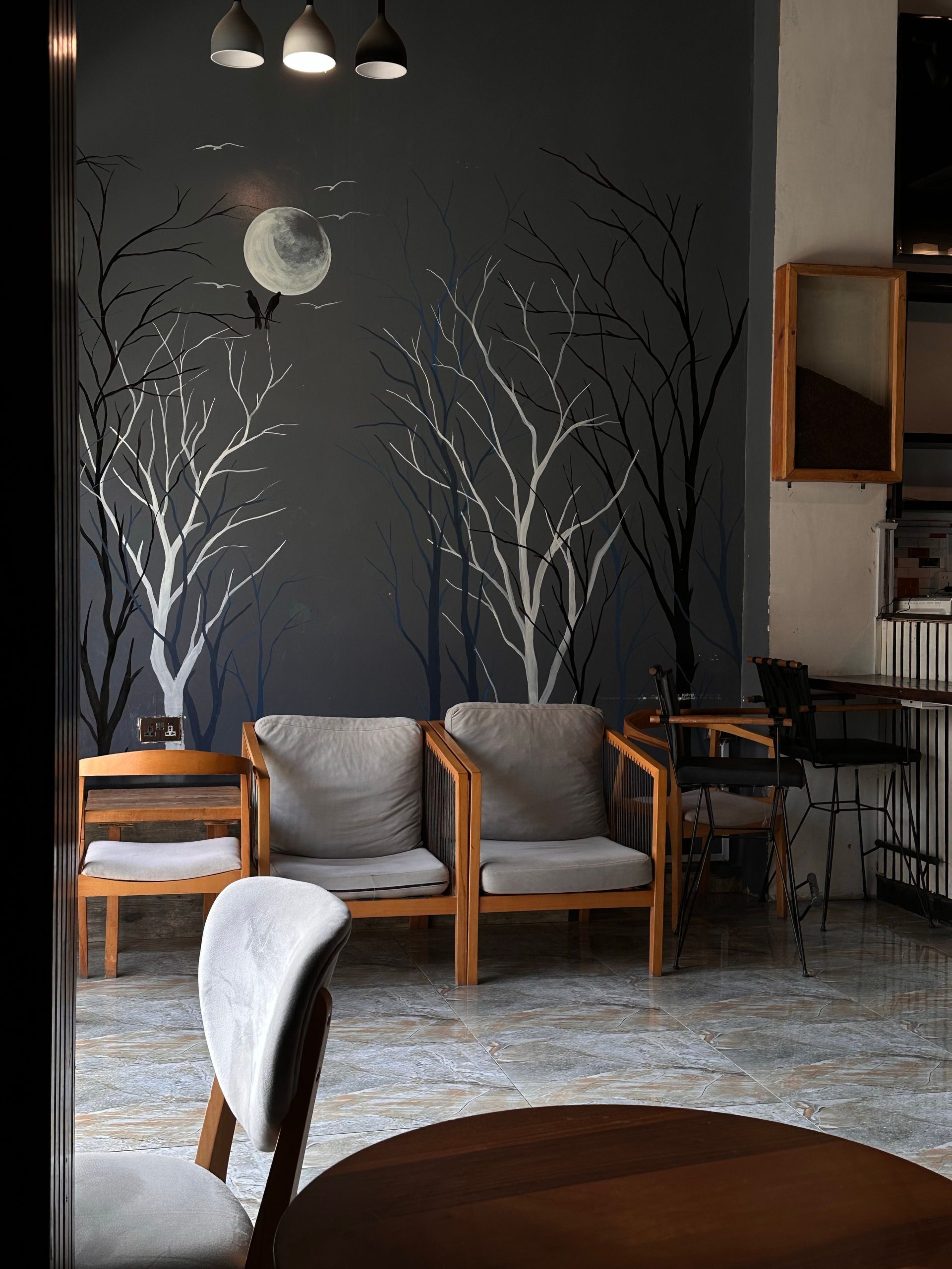 Stylish indoor seating area featuring a moonlit wall mural with bare trees and contemporary furniture.
