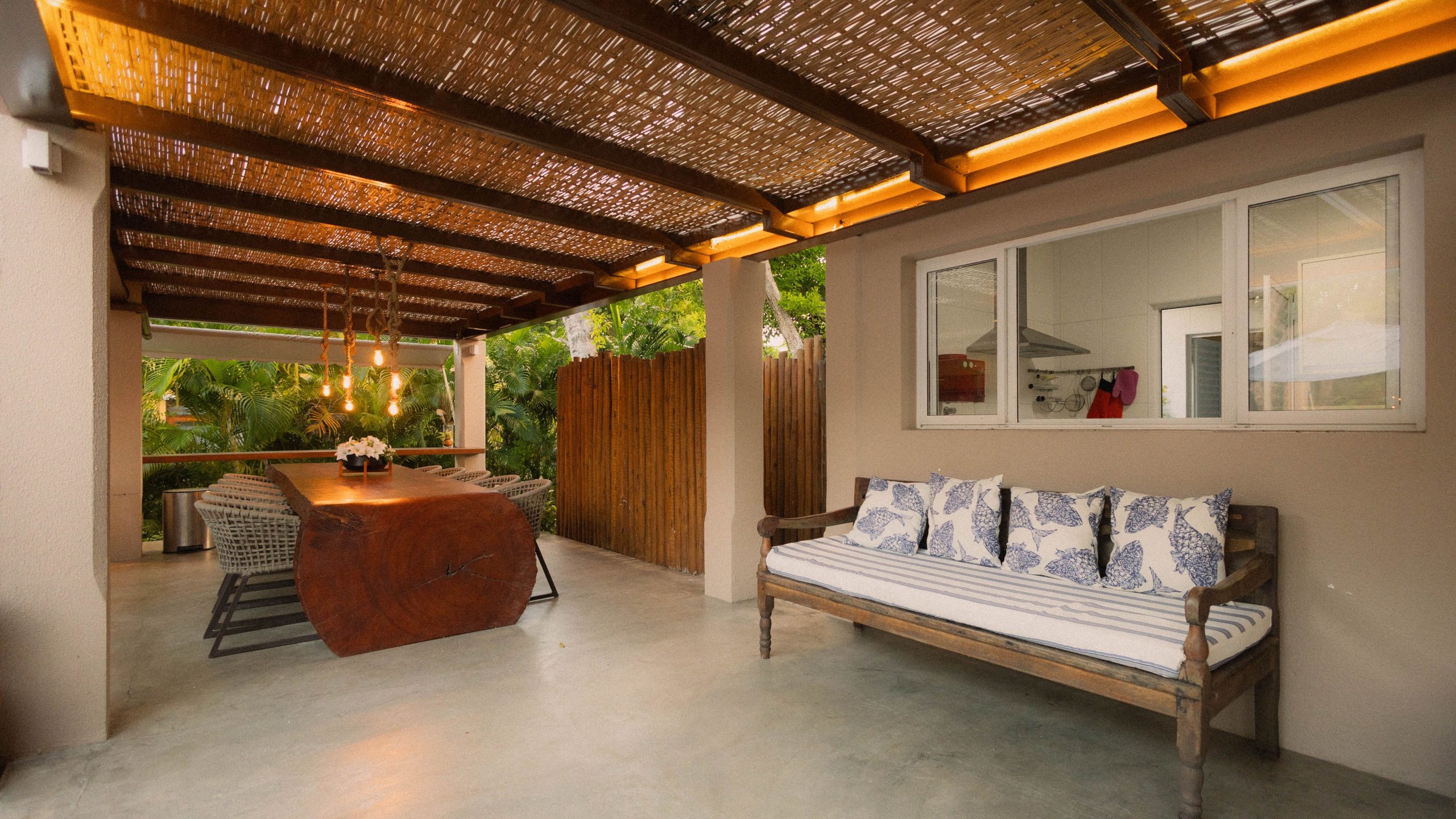 Stylish outdoor patio featuring modern wooden dining table, seating area, and ambient lighting.