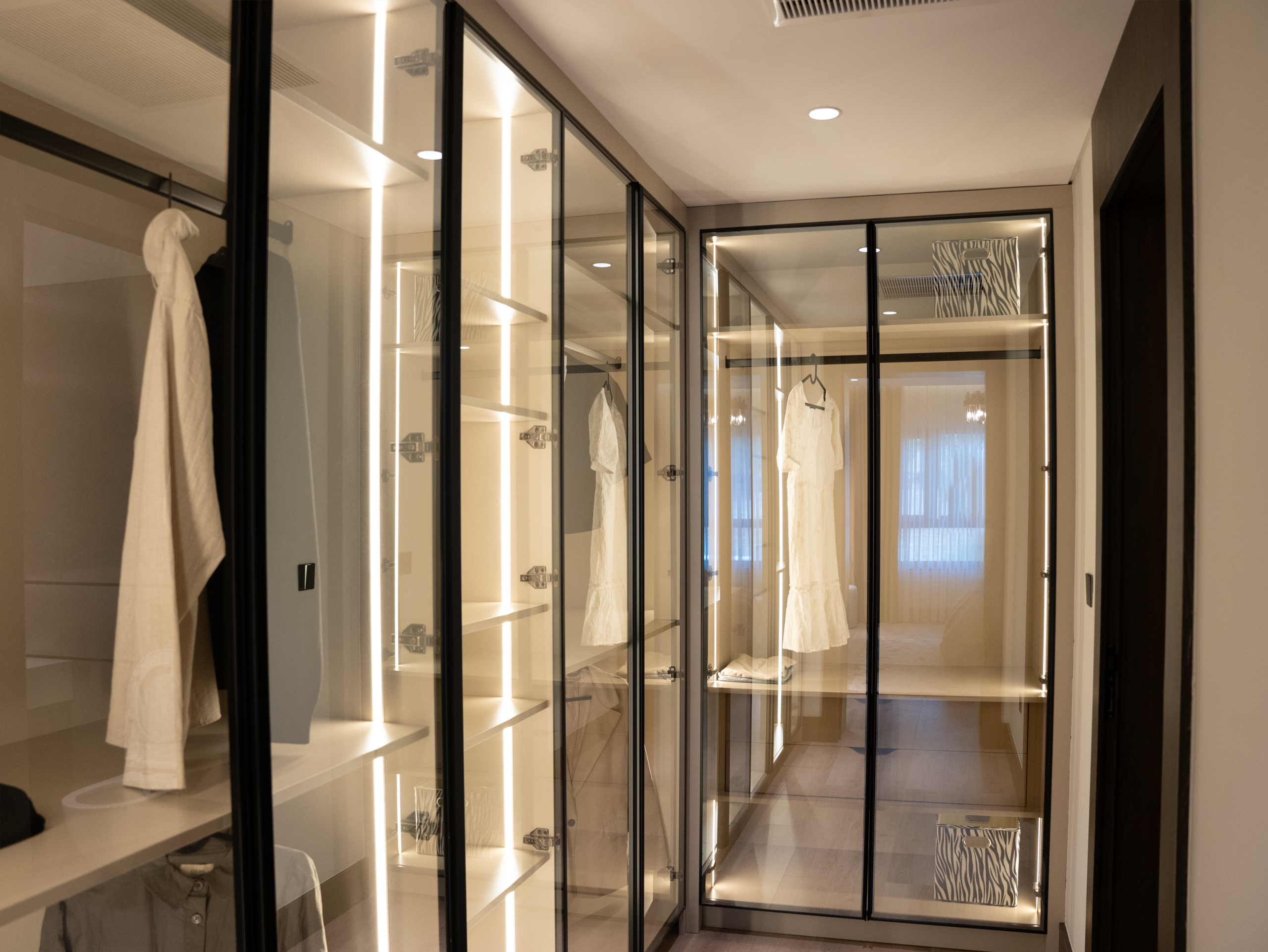 Stylish walk-in closet with glass doors and elegant lighting for a luxury home.