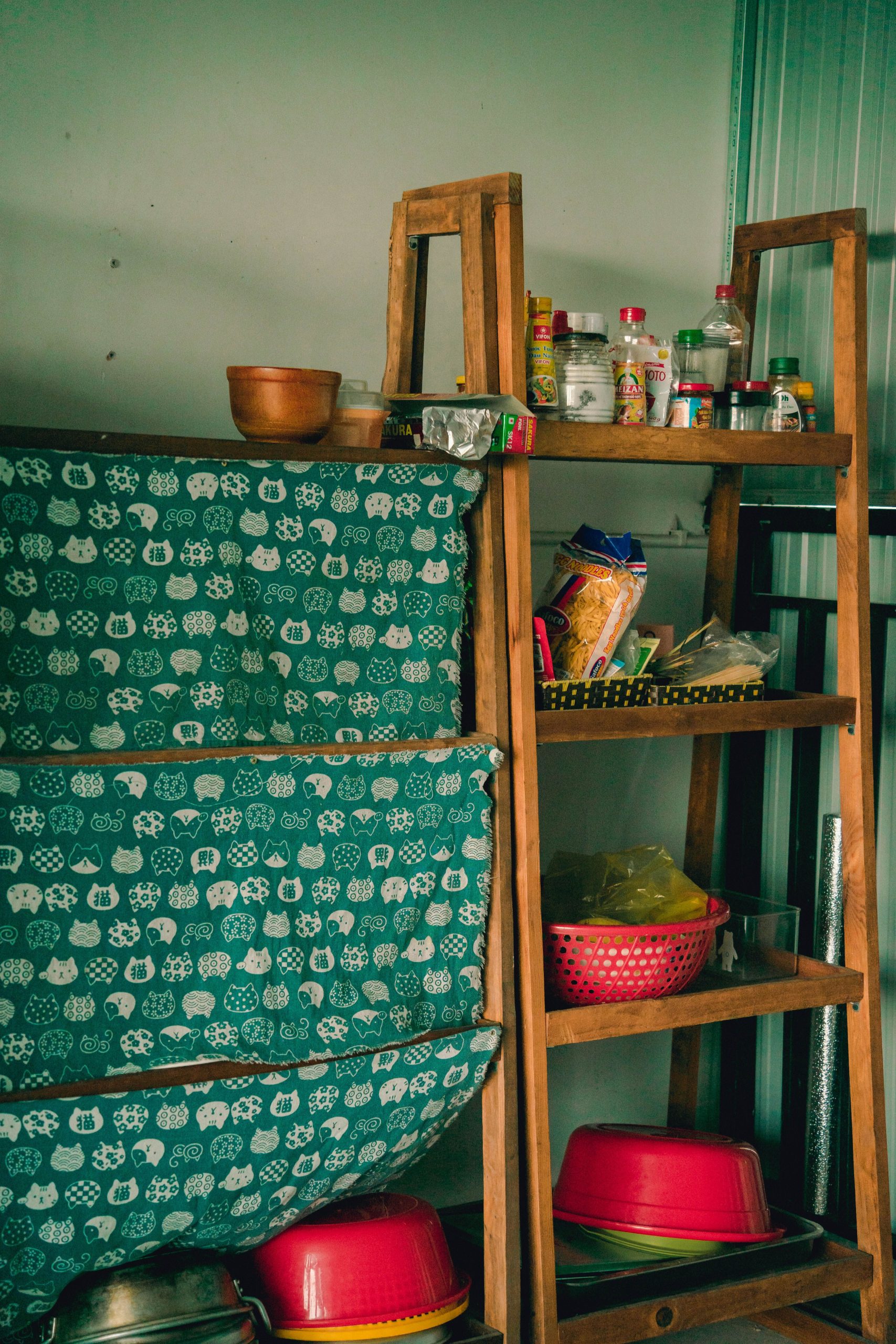 Wooden shelves in a kitchen with bowls, containers, and supplies, showcasing rustic storage solutions.
