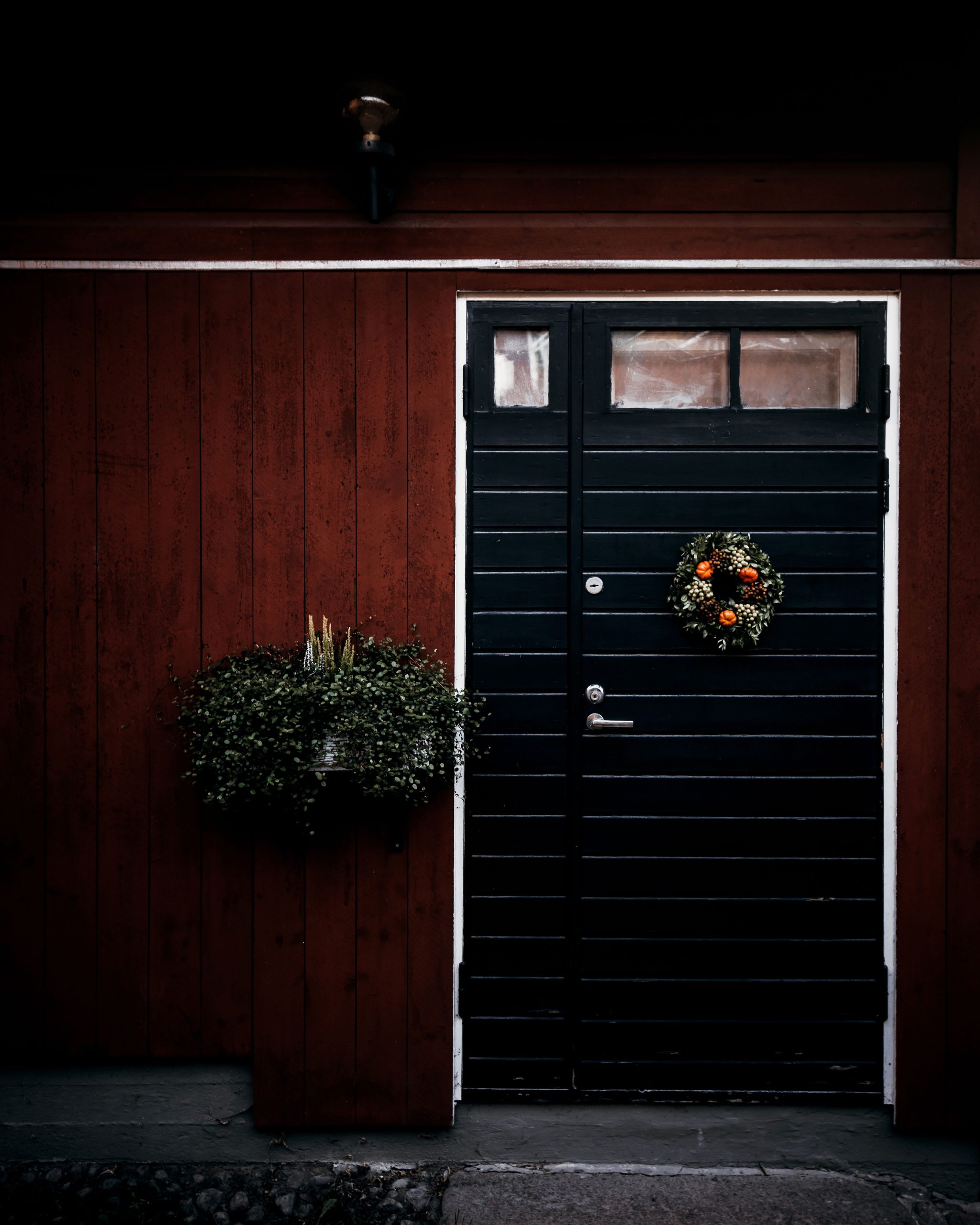 A black wooden door adorned with a festive wreath, perfect for holiday decor inspiration.