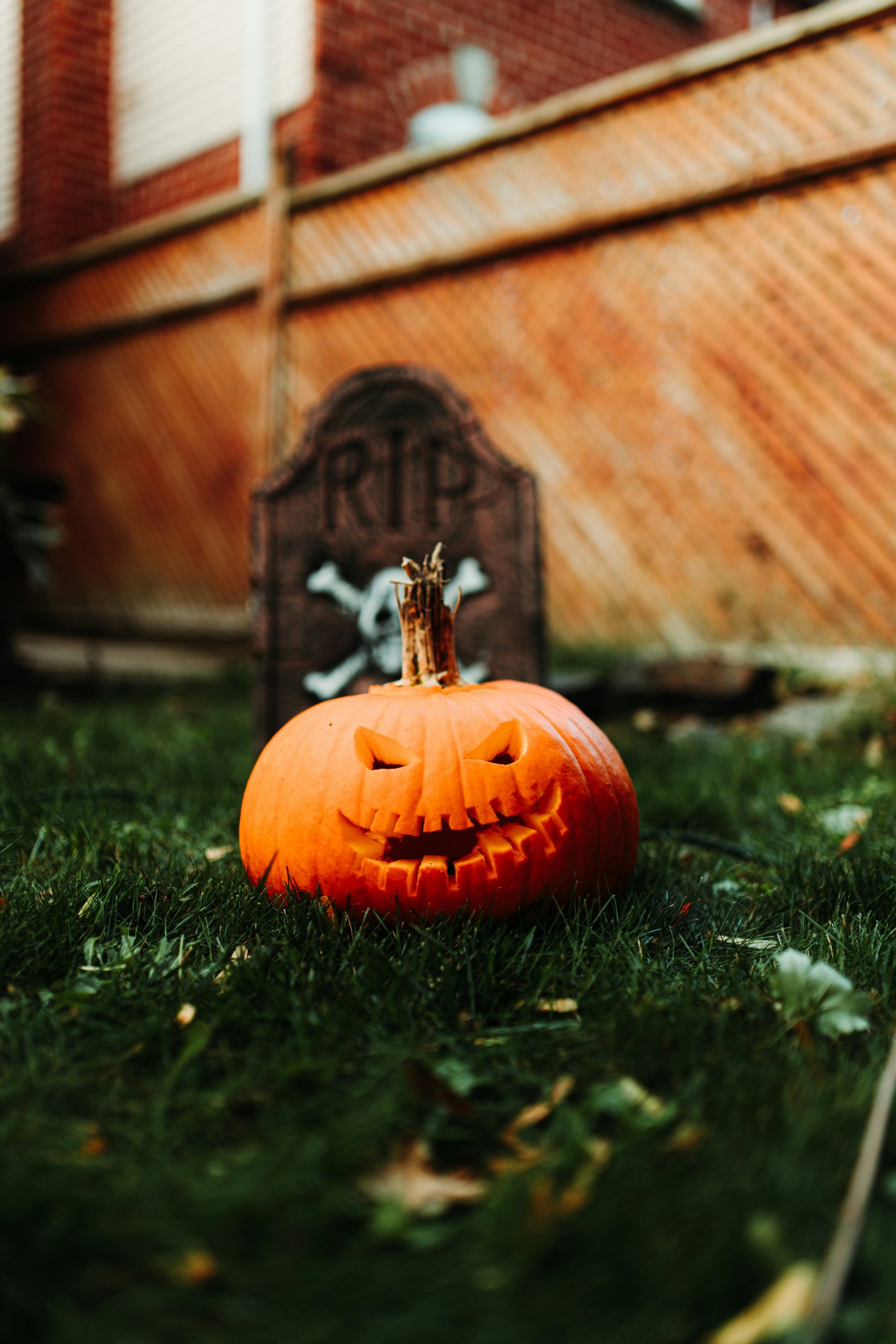a carved pumpkin sitting in the grass next to a tombstone