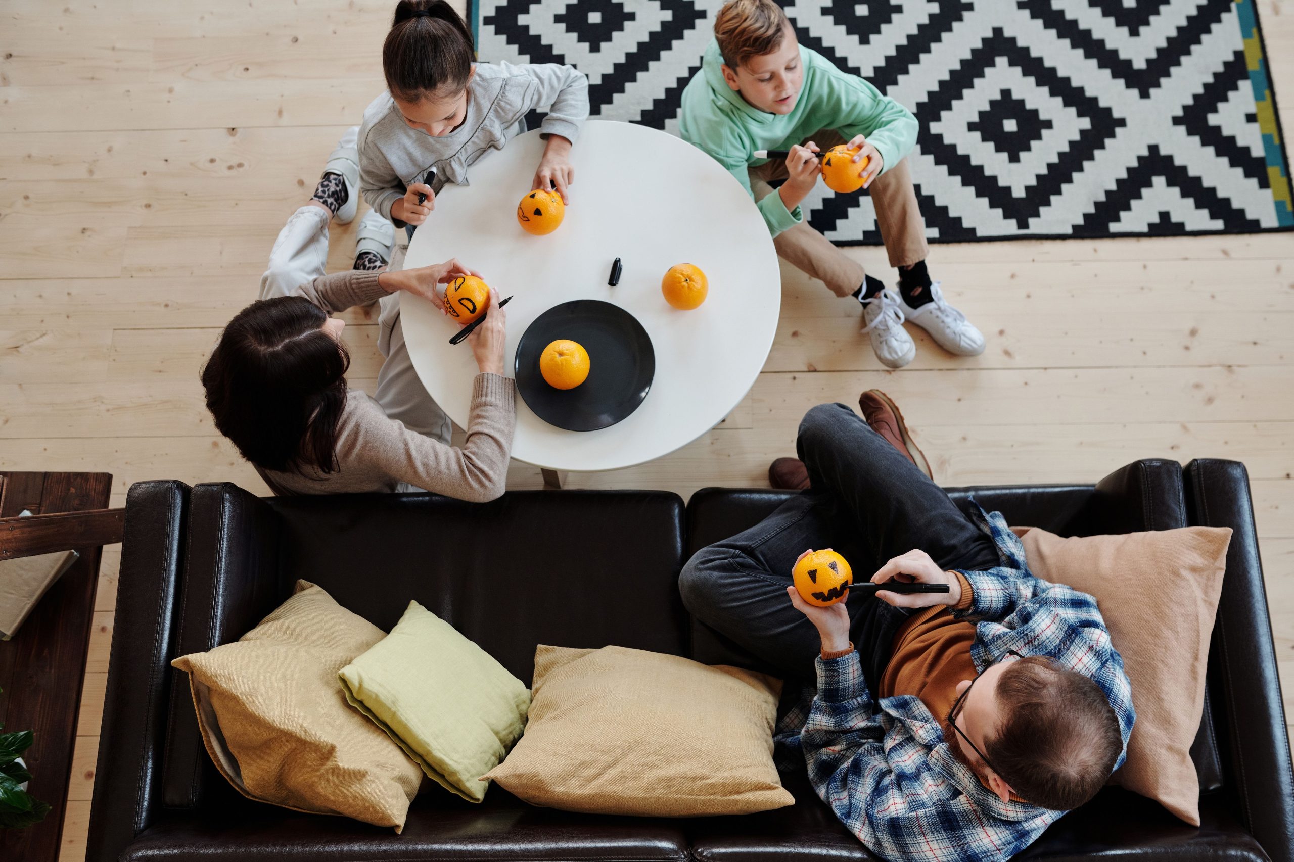 A cheerful family engages in Halloween pumpkin crafting indoors, creating fun decorations.
