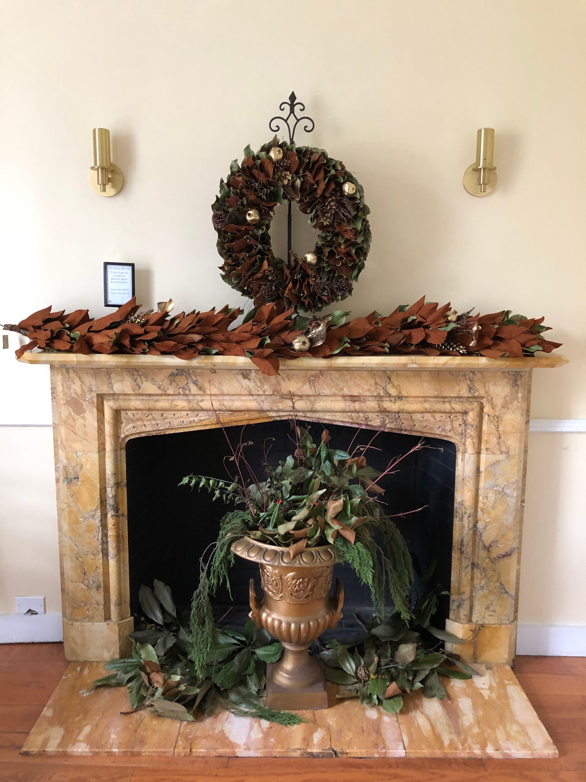 A cozy and elegant fireplace with a seasonal wreath and foliage decorations.
