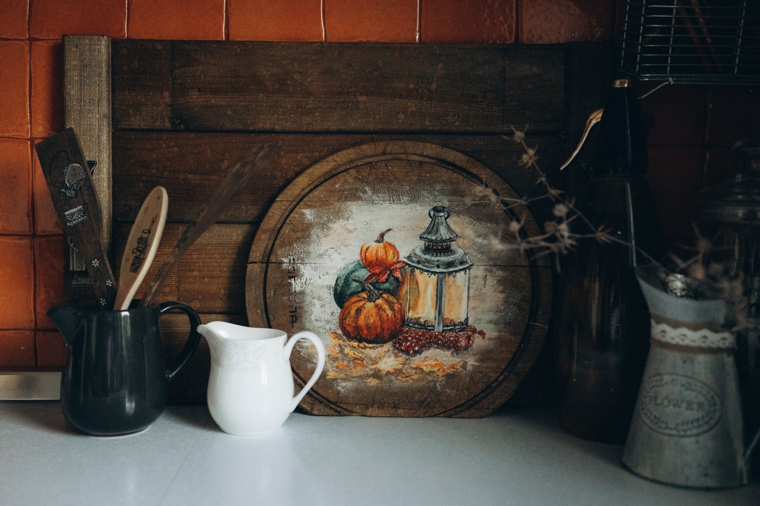 A cozy autumn-themed kitchen setup featuring rustic decor with pumpkins and a lantern.