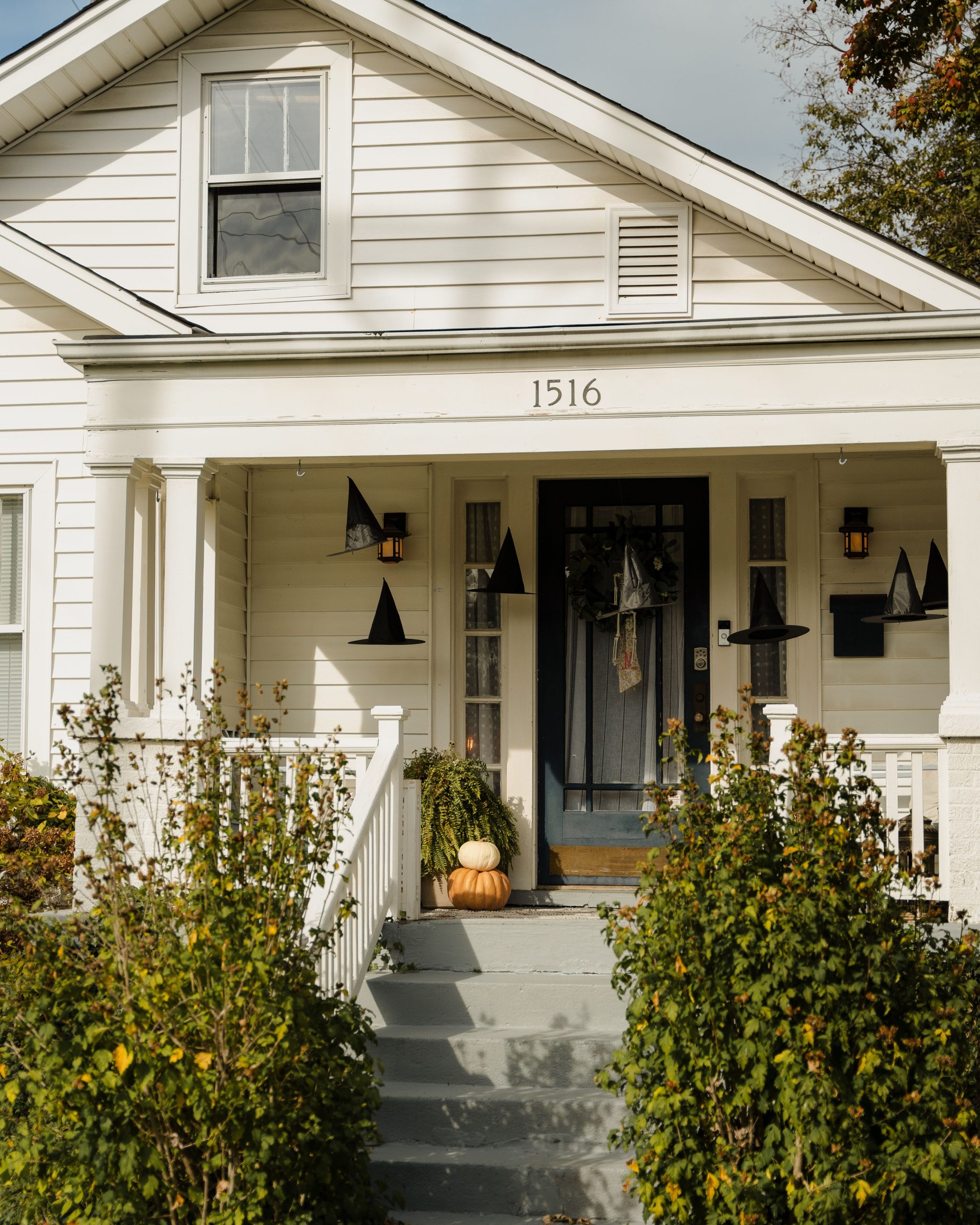 A cozy house with pumpkins and witch hats decorated for Halloween.