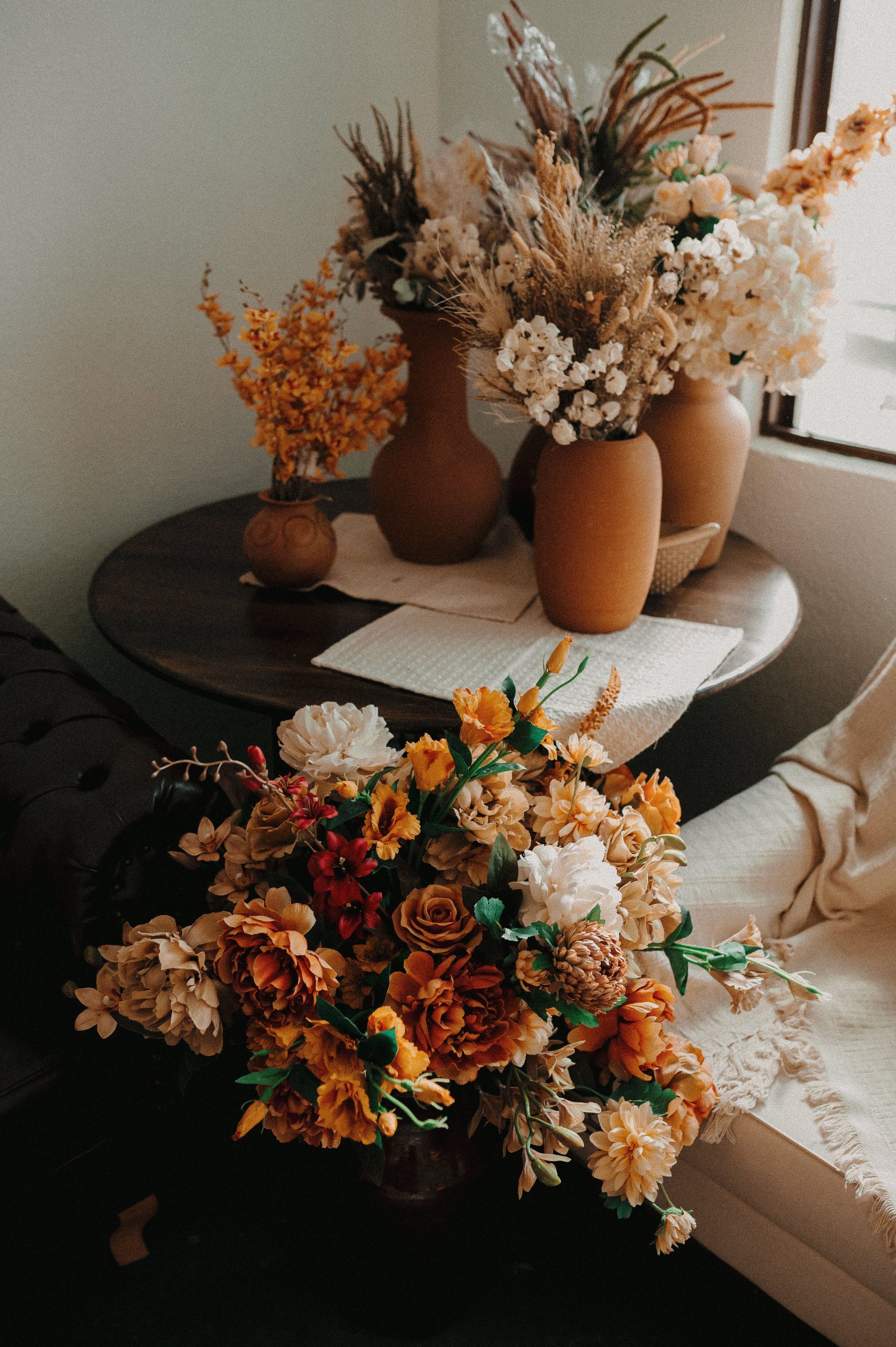 A cozy indoor display of autumn-themed floral arrangements with rustic vases.
