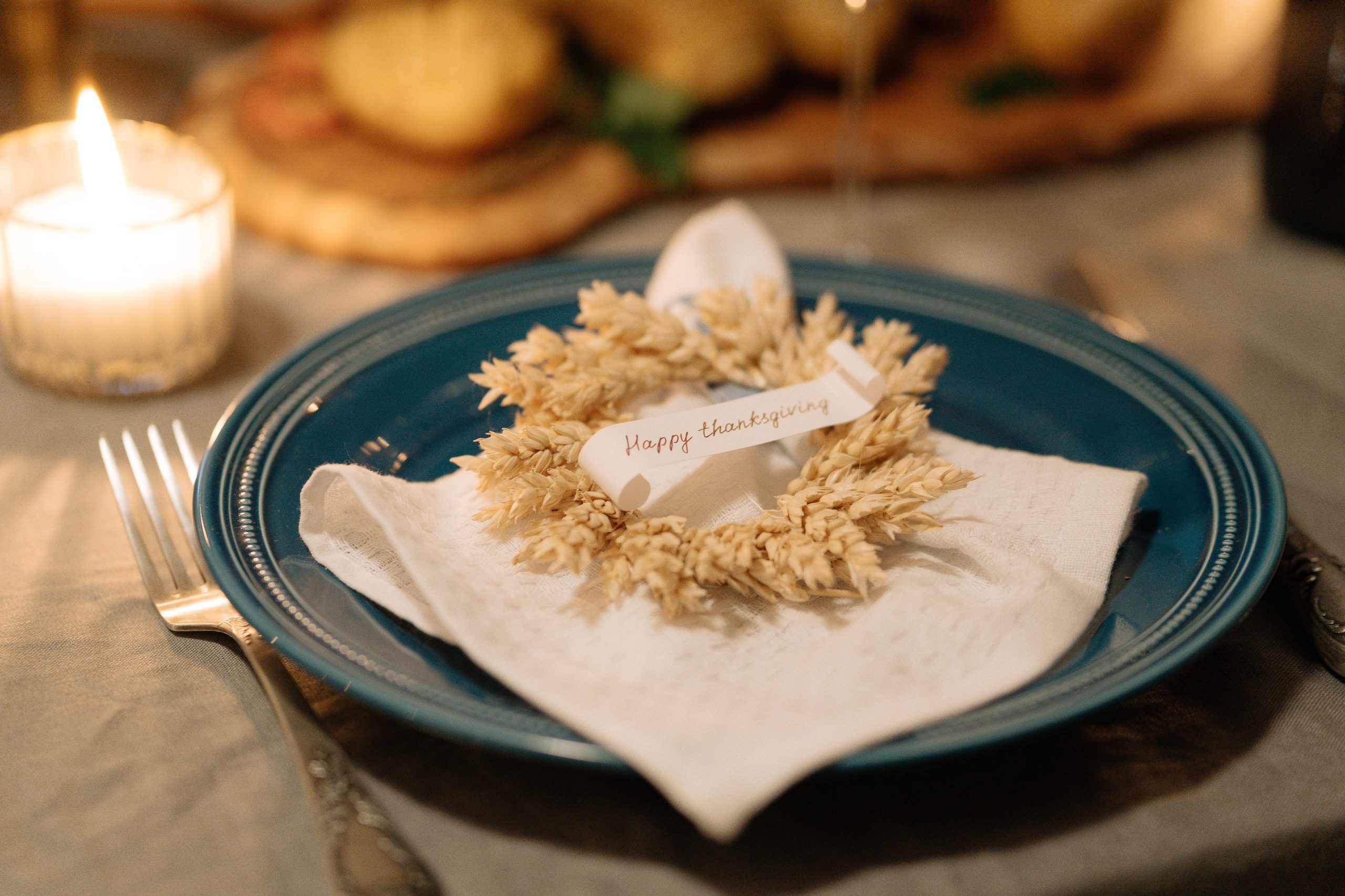 A cozy Thanksgiving table setting featuring a wreath napkin and candlelit ambiance.