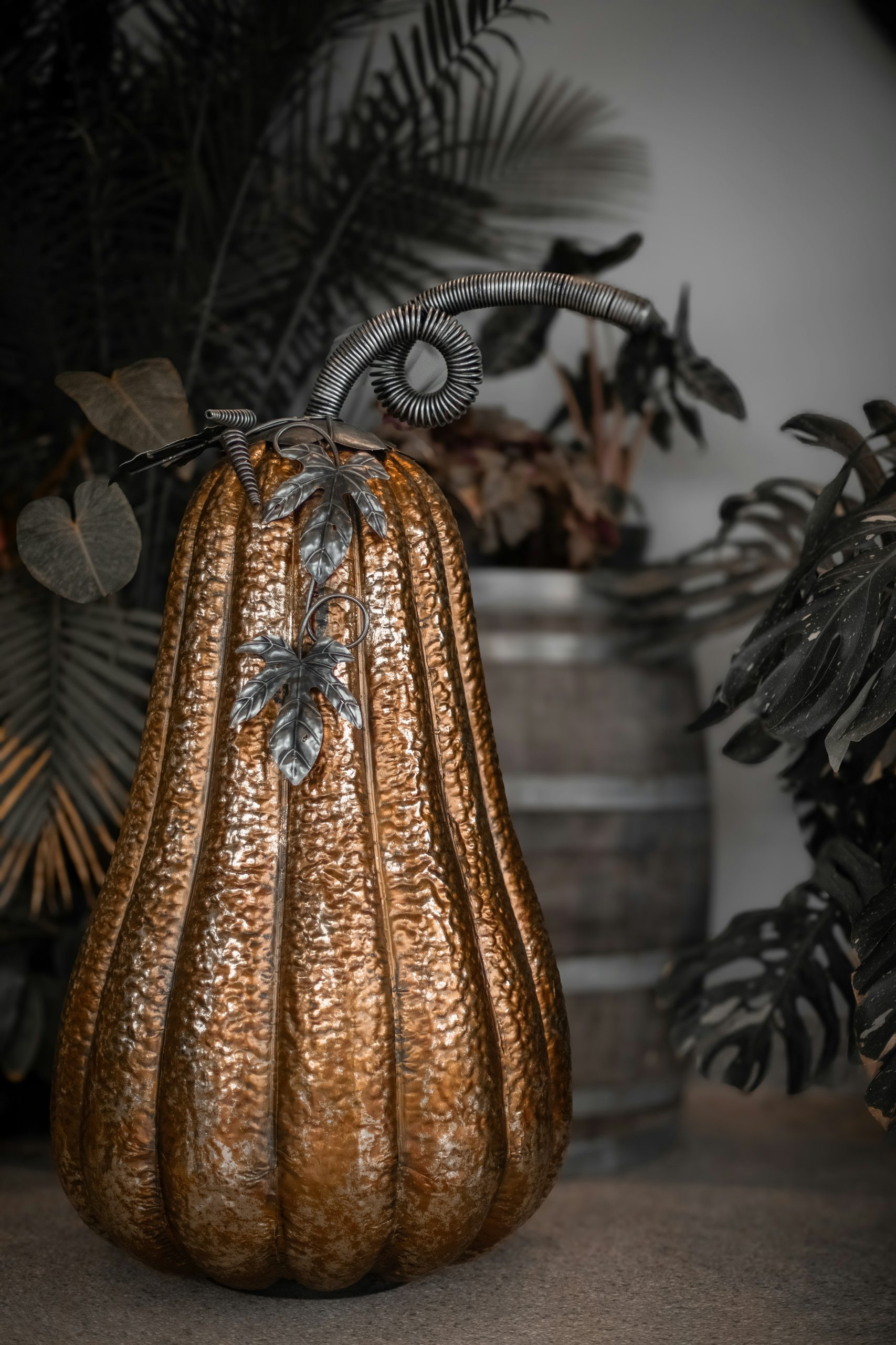 A decorative metallic pumpkin with ornate stem and leaves.