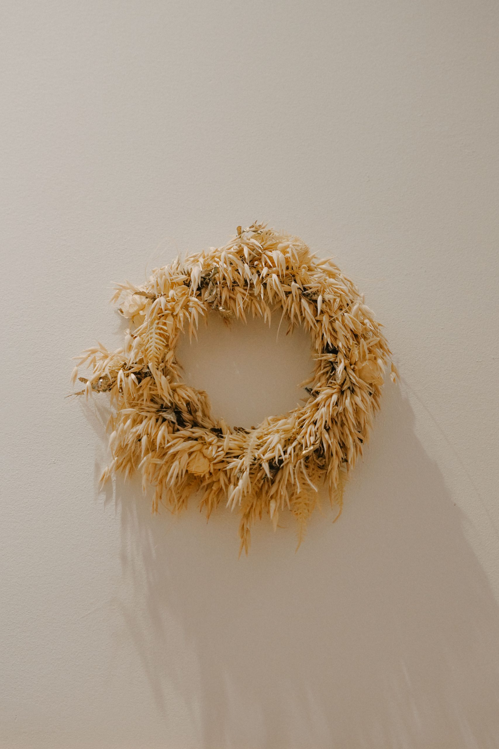 A decorative rustic wreath made of dried wheat, elegantly displayed on a neutral wall.