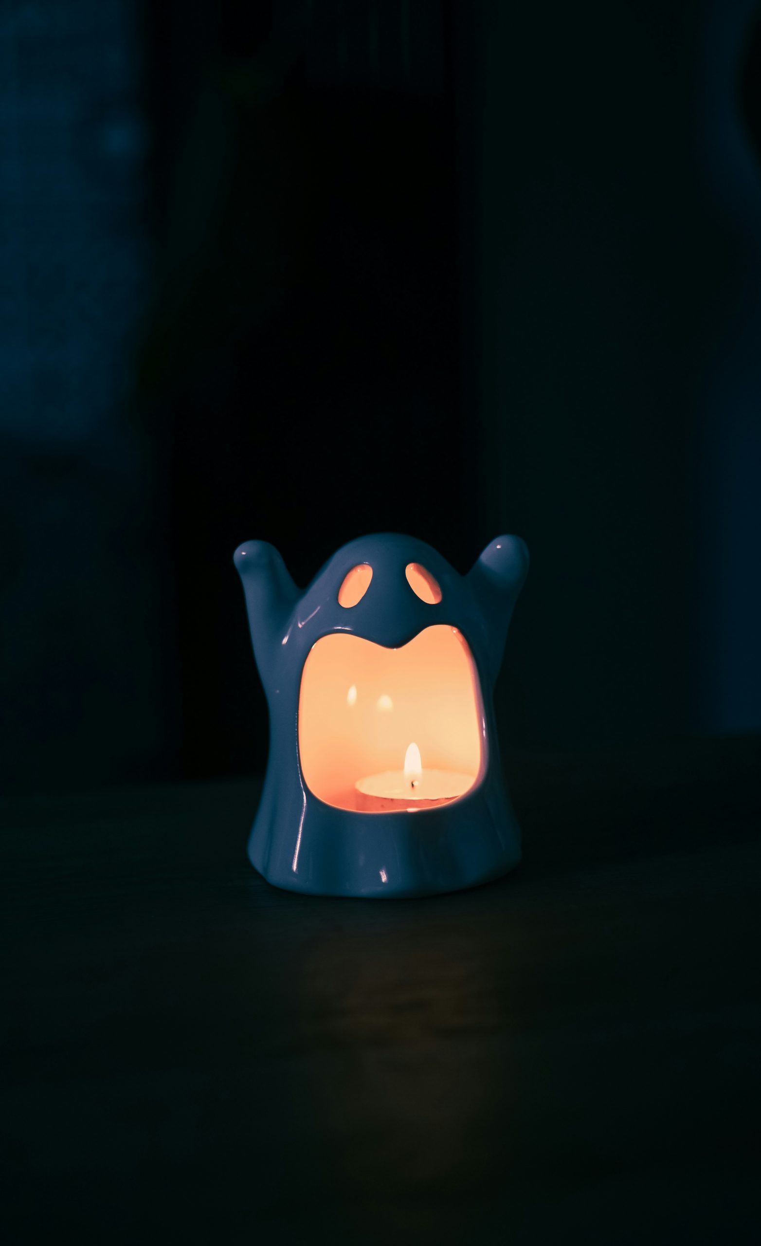 A ghost-shaped lantern with a lit candle inside