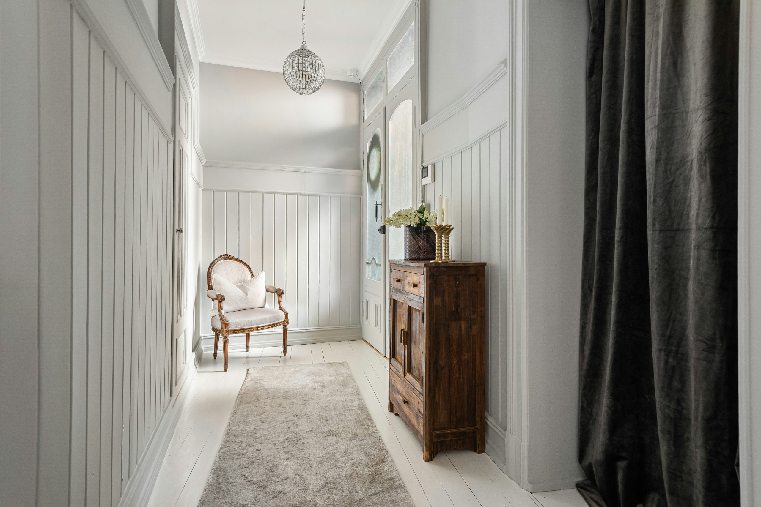 A hallway with a chair and a rug on the floor