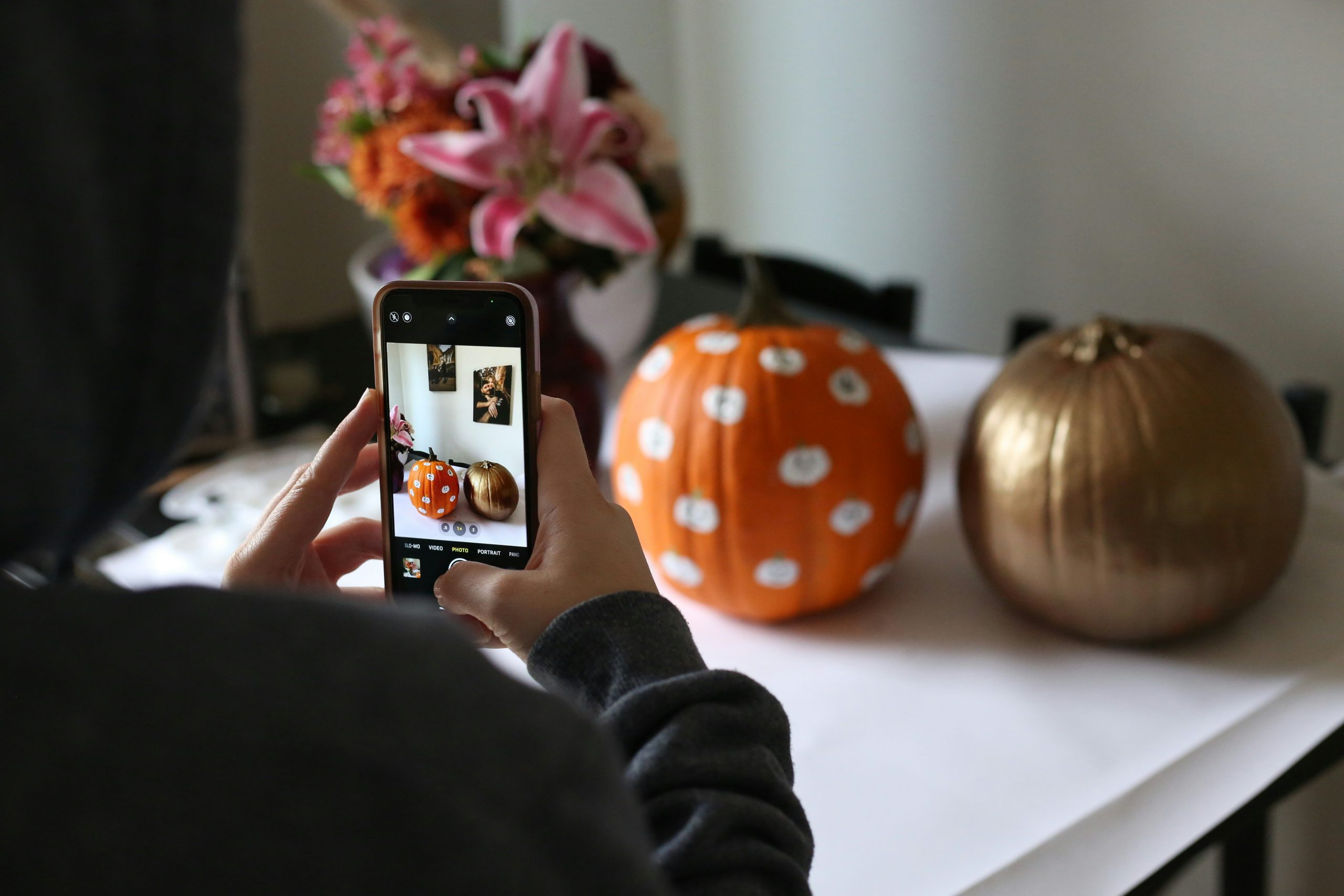 a person taking a picture of a pumpkin