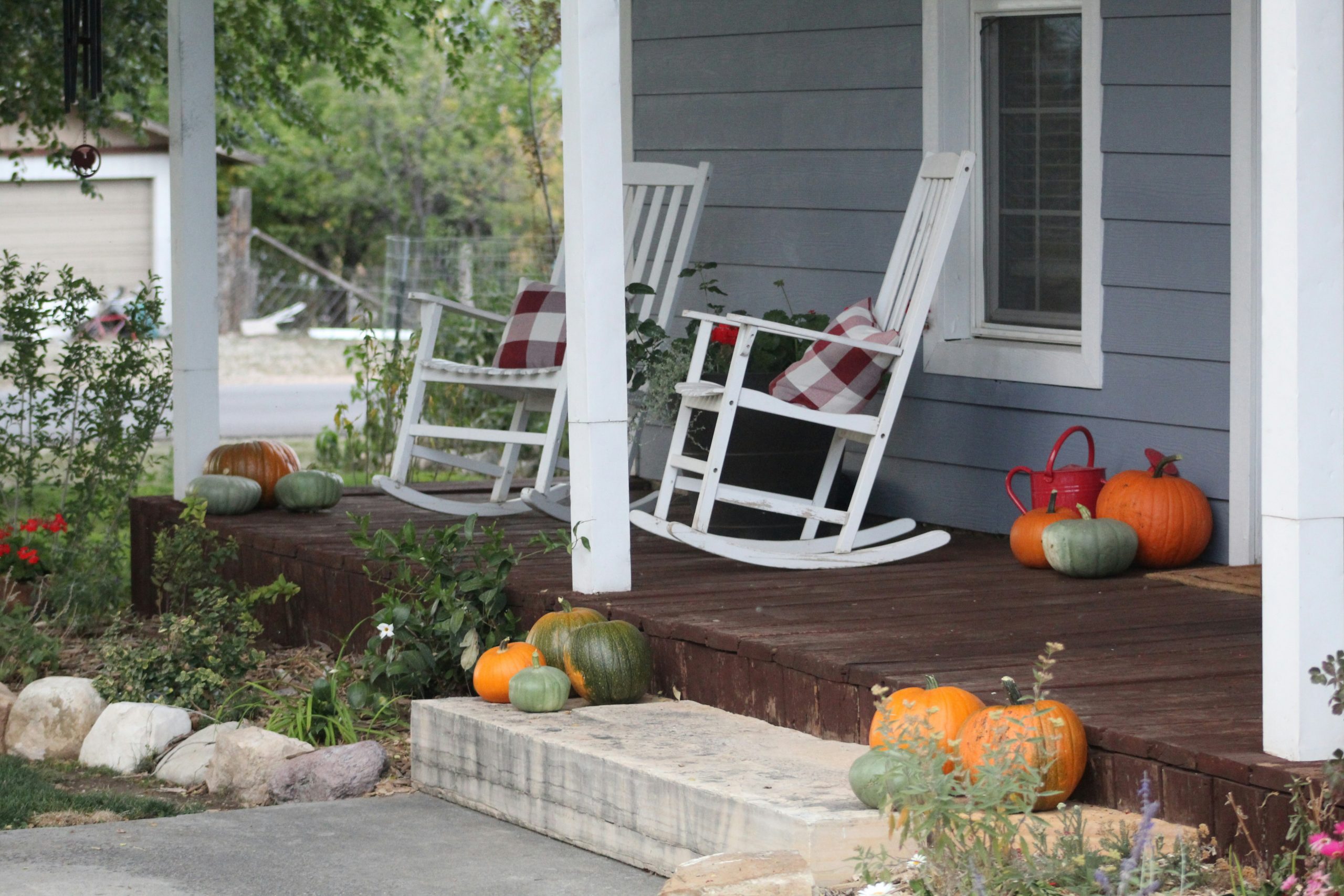 a porch with rocking chairs and pumpkins on it