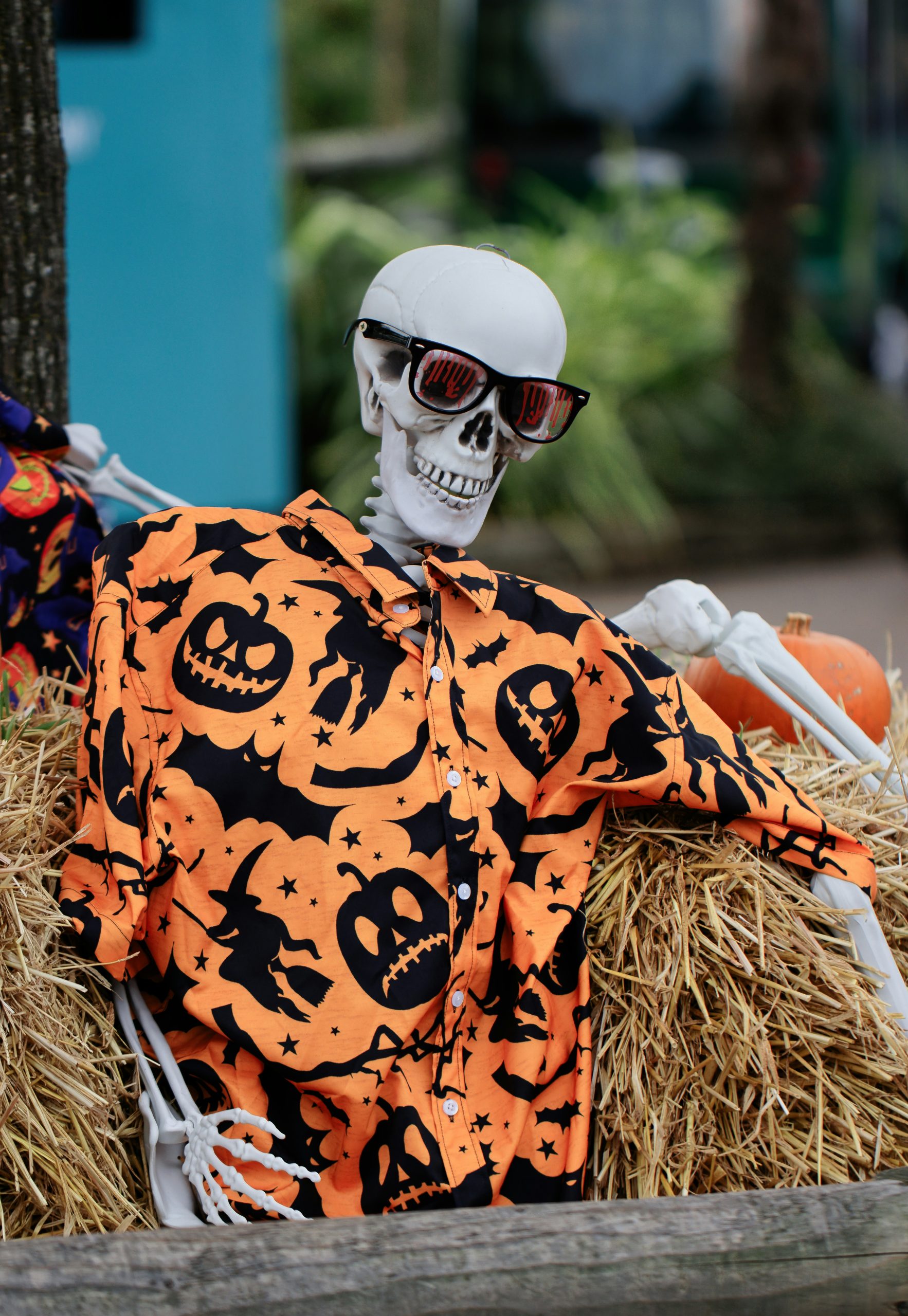 A skeleton in a pumpkin costume sitting in a pile of hay