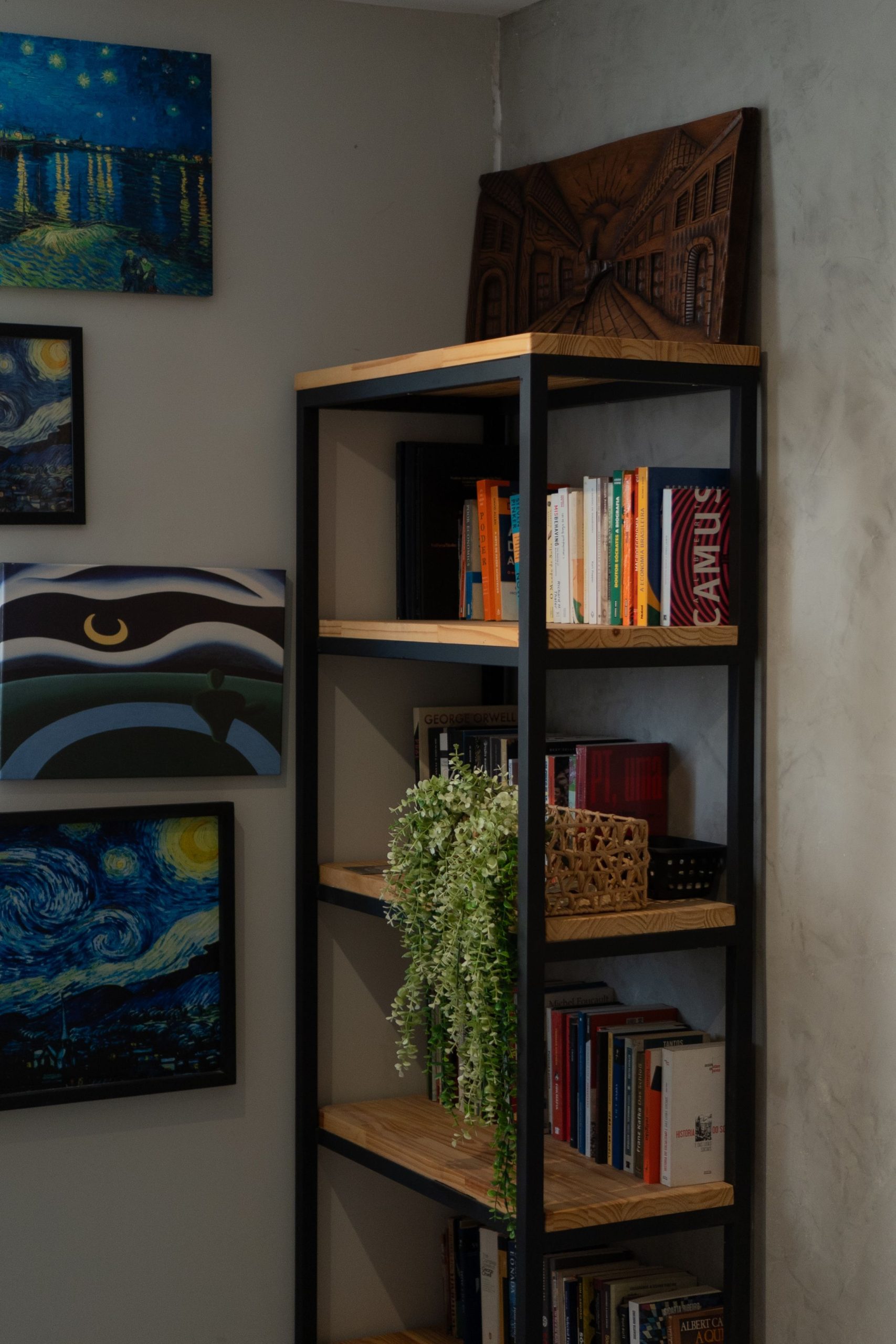 A stylish bookshelf in a cozy corner adorned with art and plants.