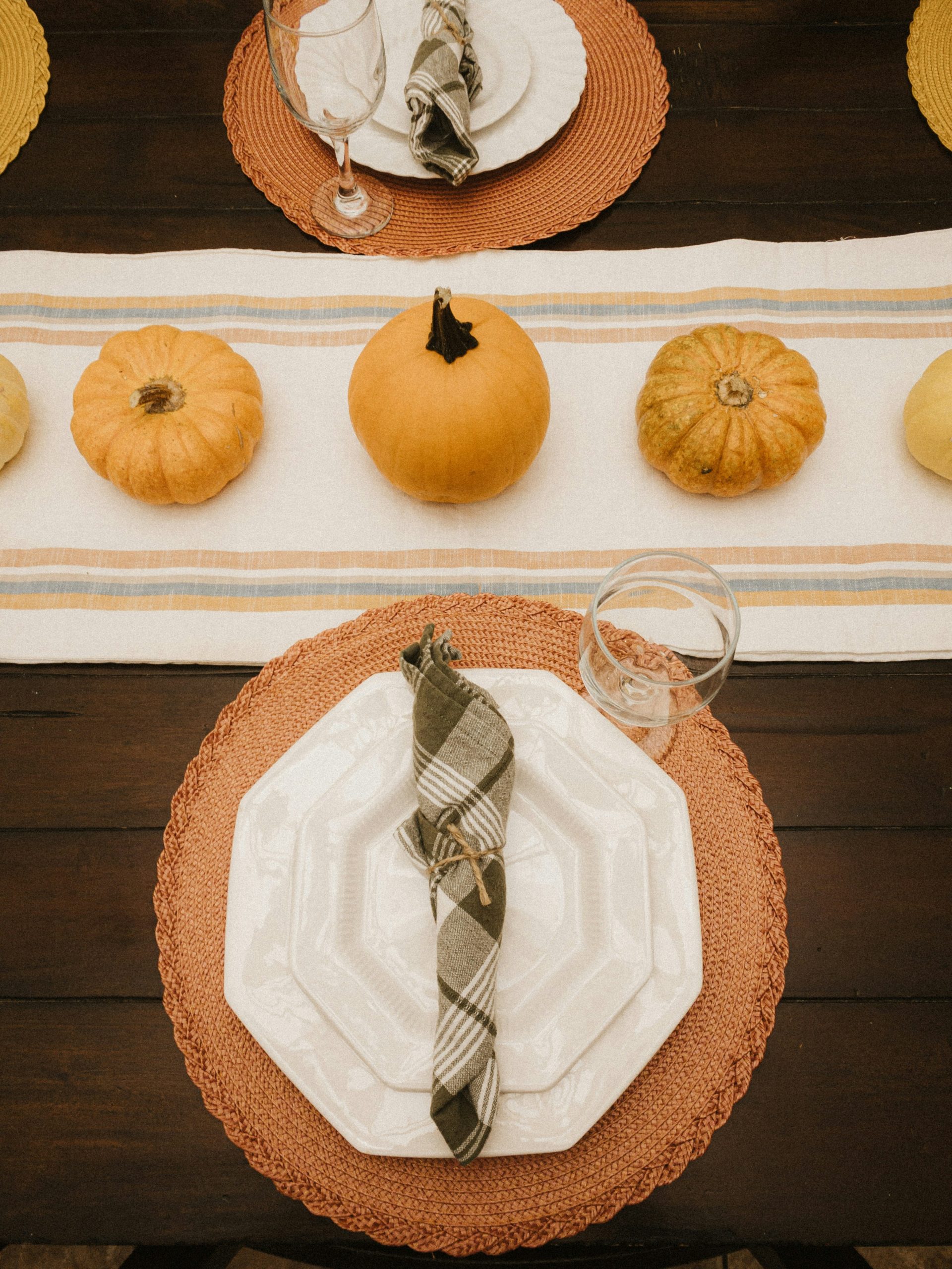 a table set for a thanksgiving dinner with pumpkins and gourds