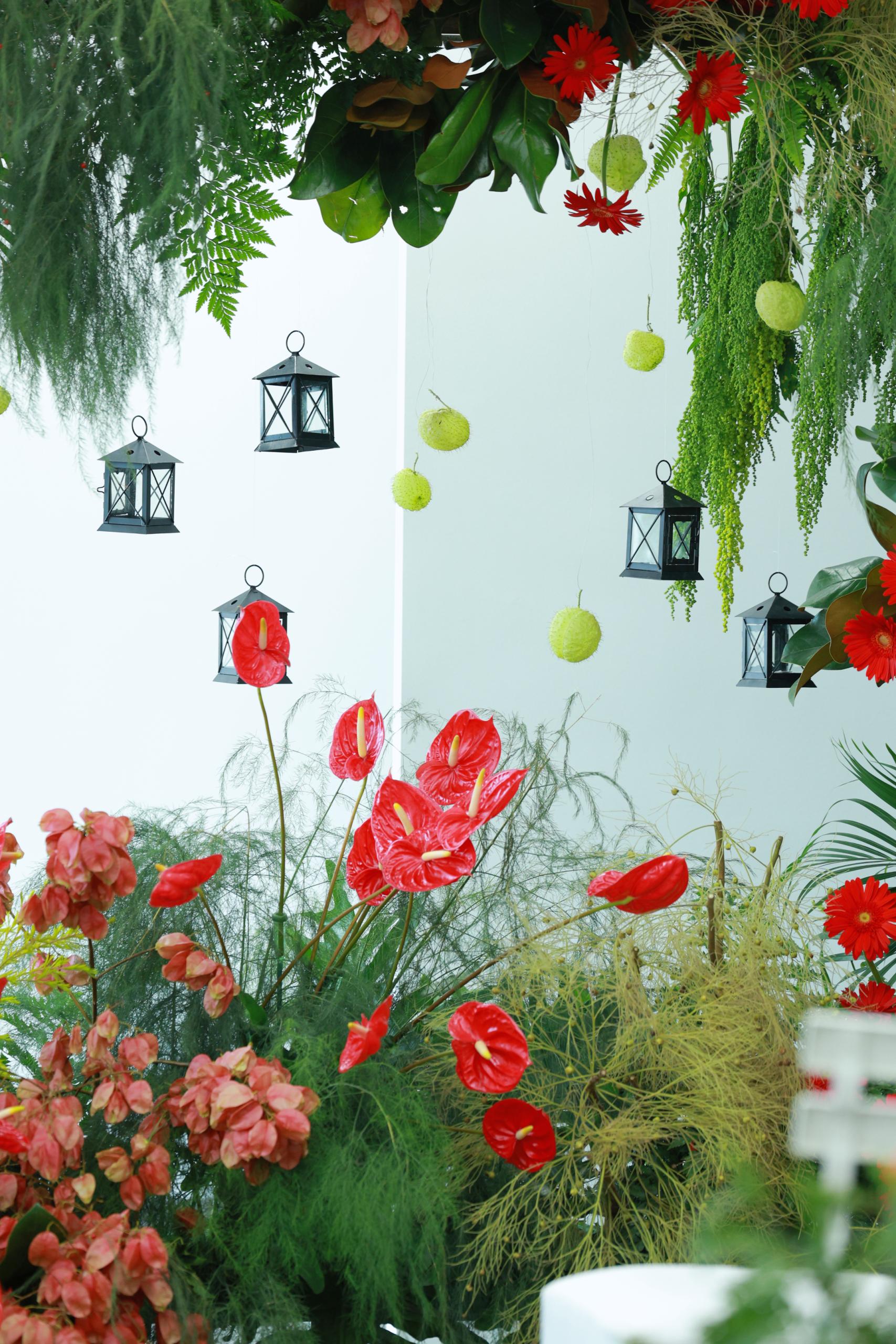 A vibrant floral arrangement with red flowers and decorative lanterns, creating a lively indoor scene.