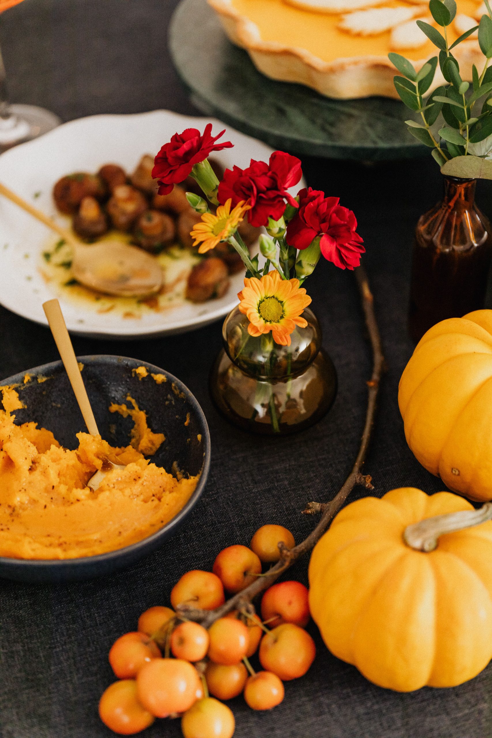 A warm autumn table setting featuring pumpkins, flowers, and delicious home-cooked dishes.