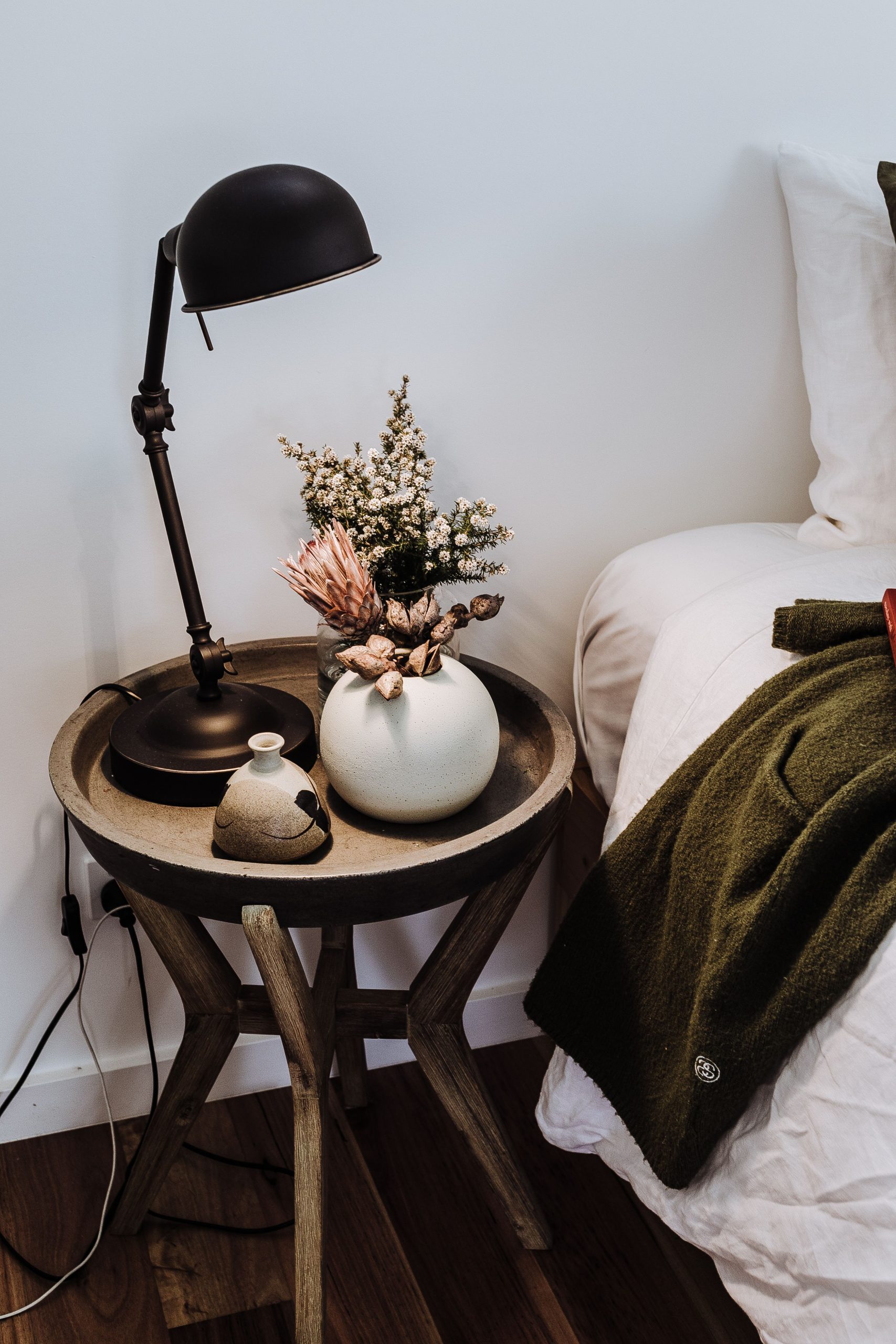 Bedroom interior with dried bouquet in vase near lamp and cozy bed in house
