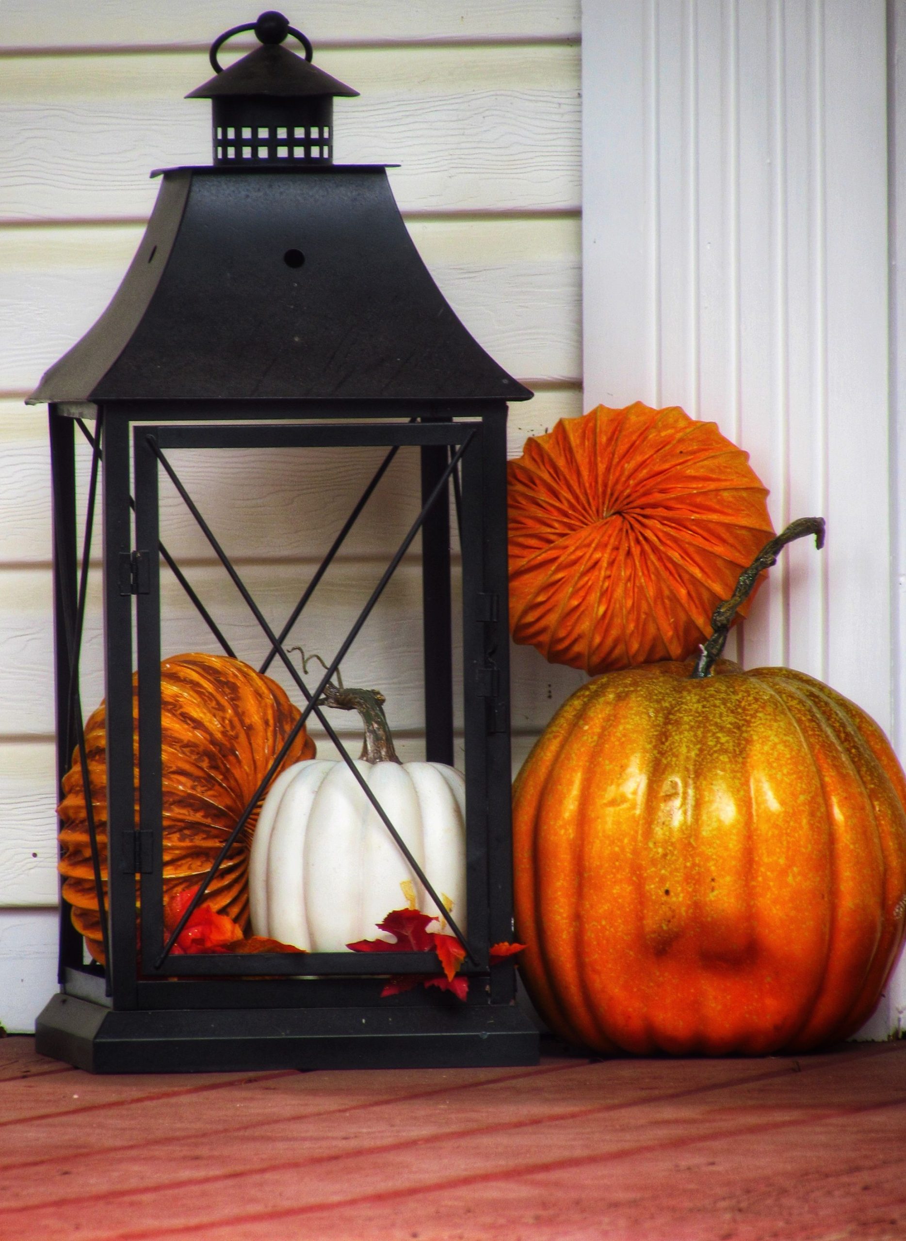 Charming autumn scene with pumpkins and lantern on a porch, perfect for fall decor ideas.