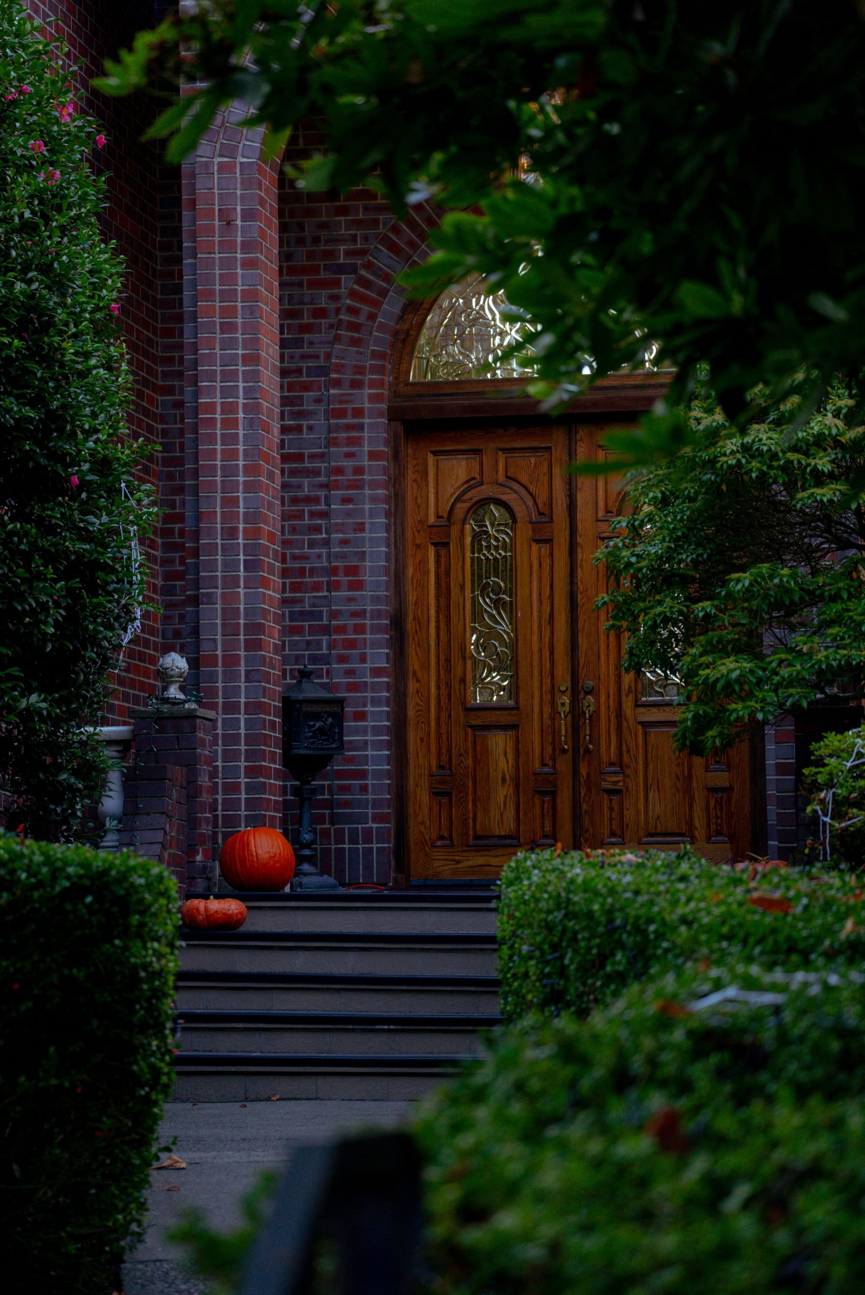 Charming brick house entrance decorated with pumpkins, emphasizing fall ambiance.