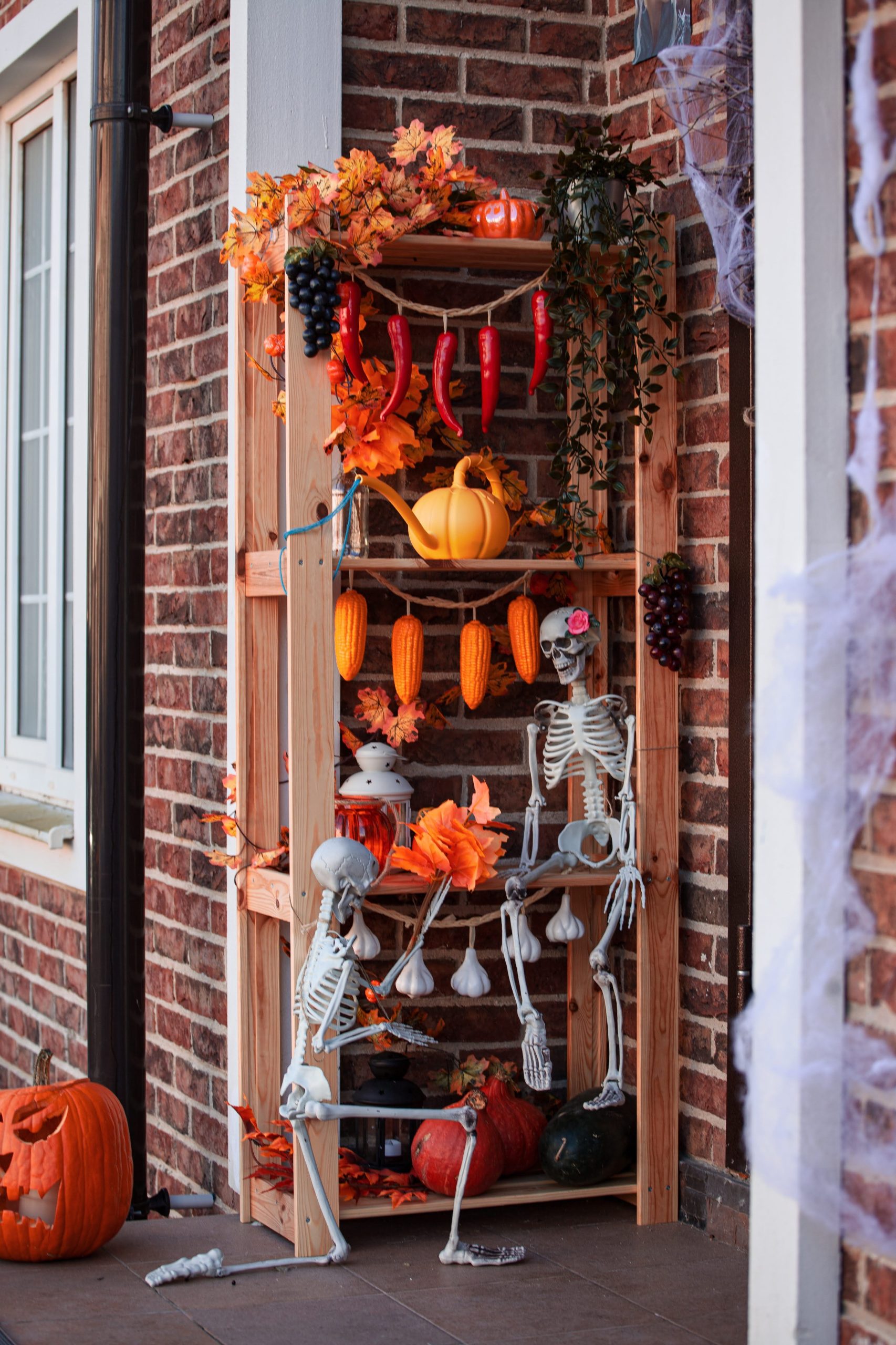 Charming Halloween setup featuring skeletons, pumpkins, and autumn decor on a shelf.