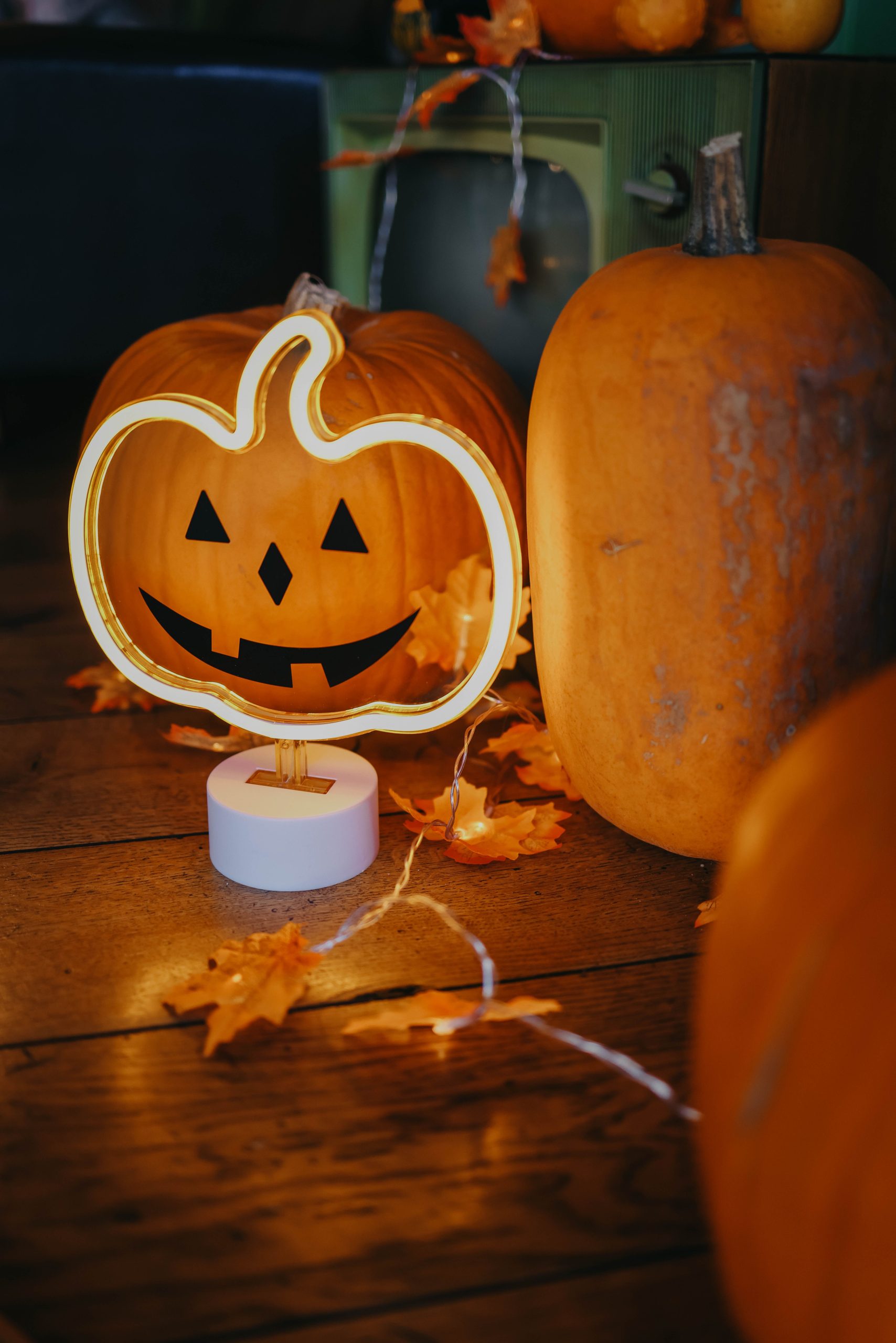 Charming indoor Halloween scene with pumpkins, warm lighting, and autumn leaves.