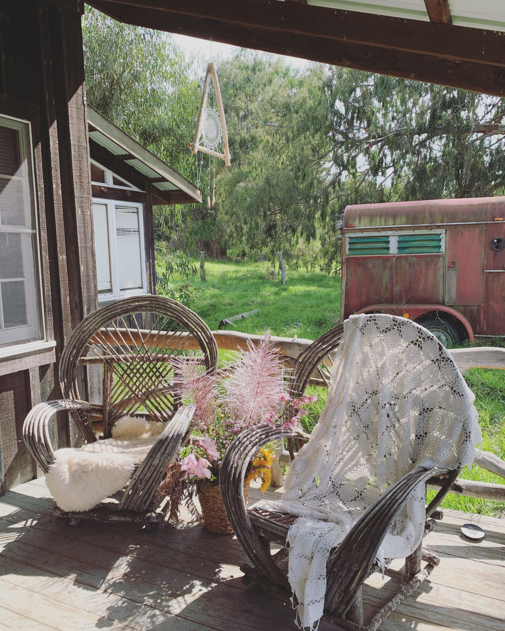 Charming porch featuring rustic chairs, lush greenery, and a vintage vibe, perfect for relaxing outdoors.