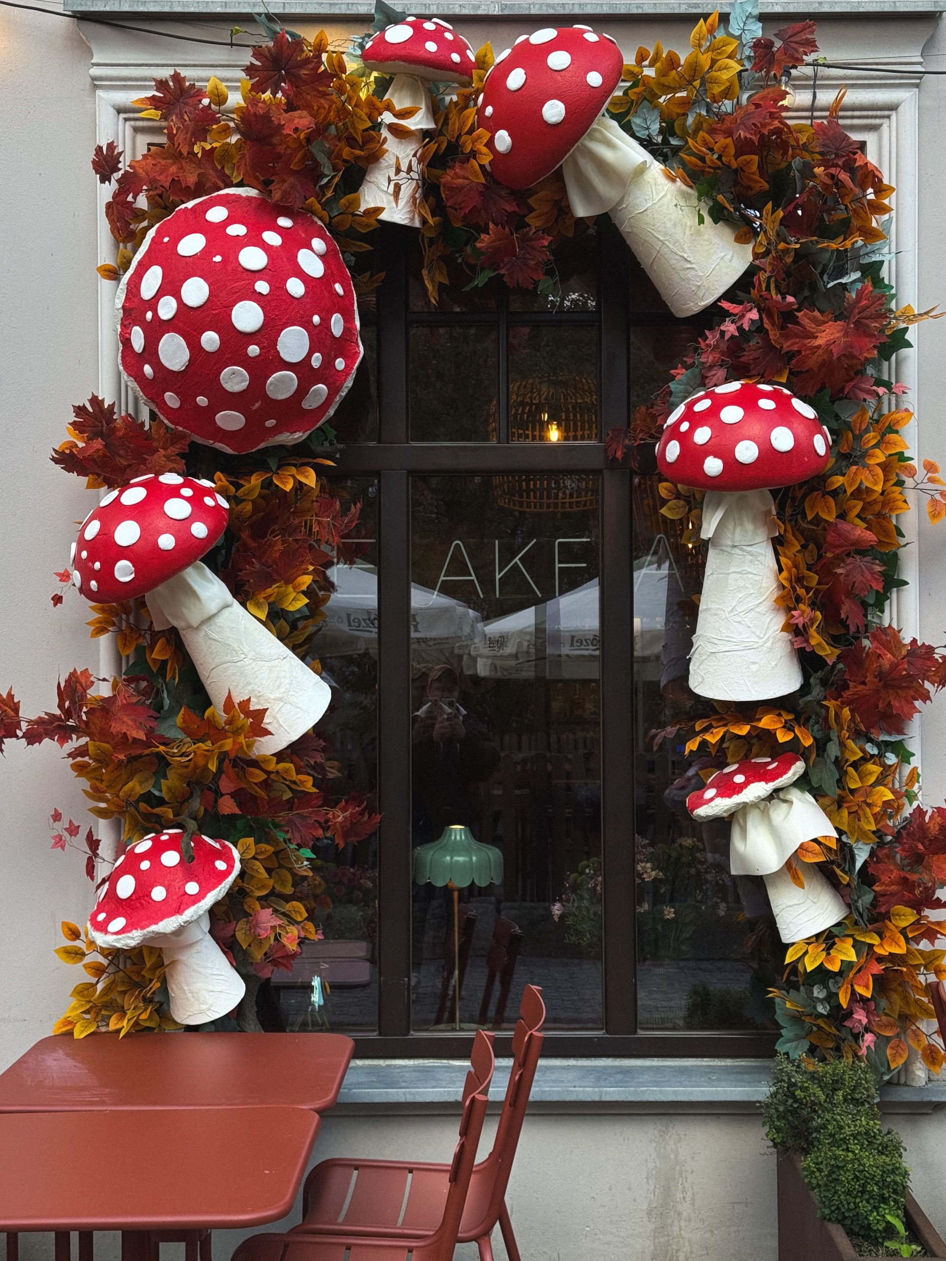 Charming window decoration featuring red and white spotted mushrooms and autumn leaves.