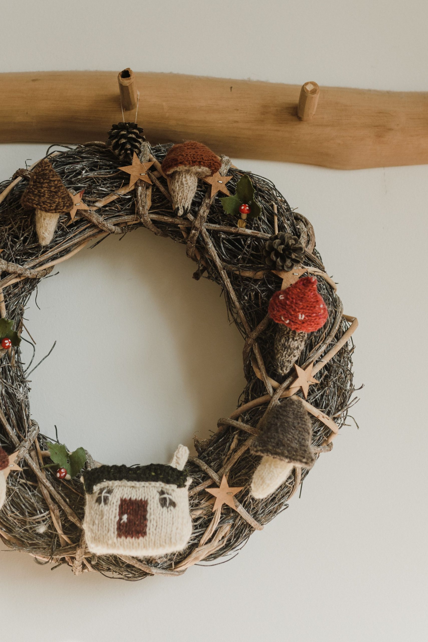 Close-up of a rustic Christmas wreath with knitted mushrooms and house decoration.