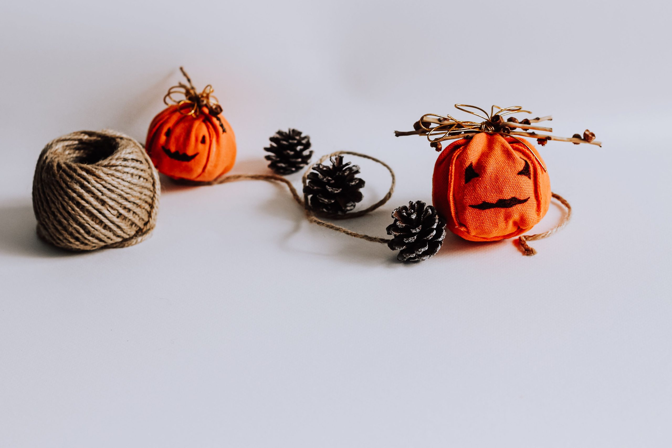 Close-up of rustic Halloween decorations featuring twine, pinecones, and small fabric pumpkins.