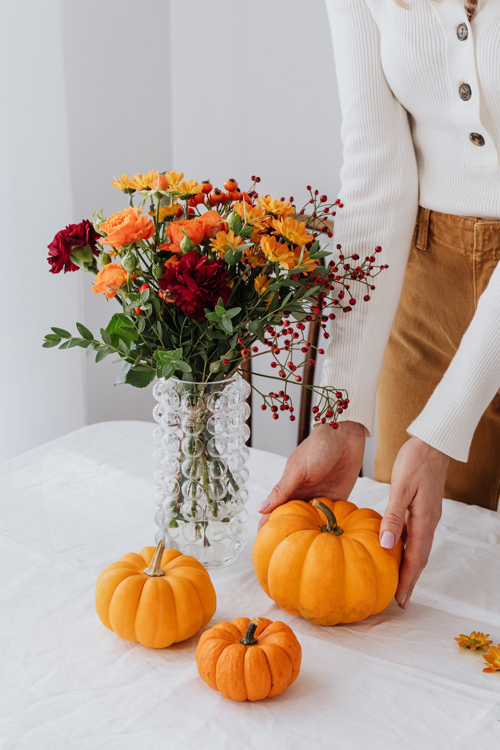 Colorful autumn floral arrangement and pumpkins on a table.