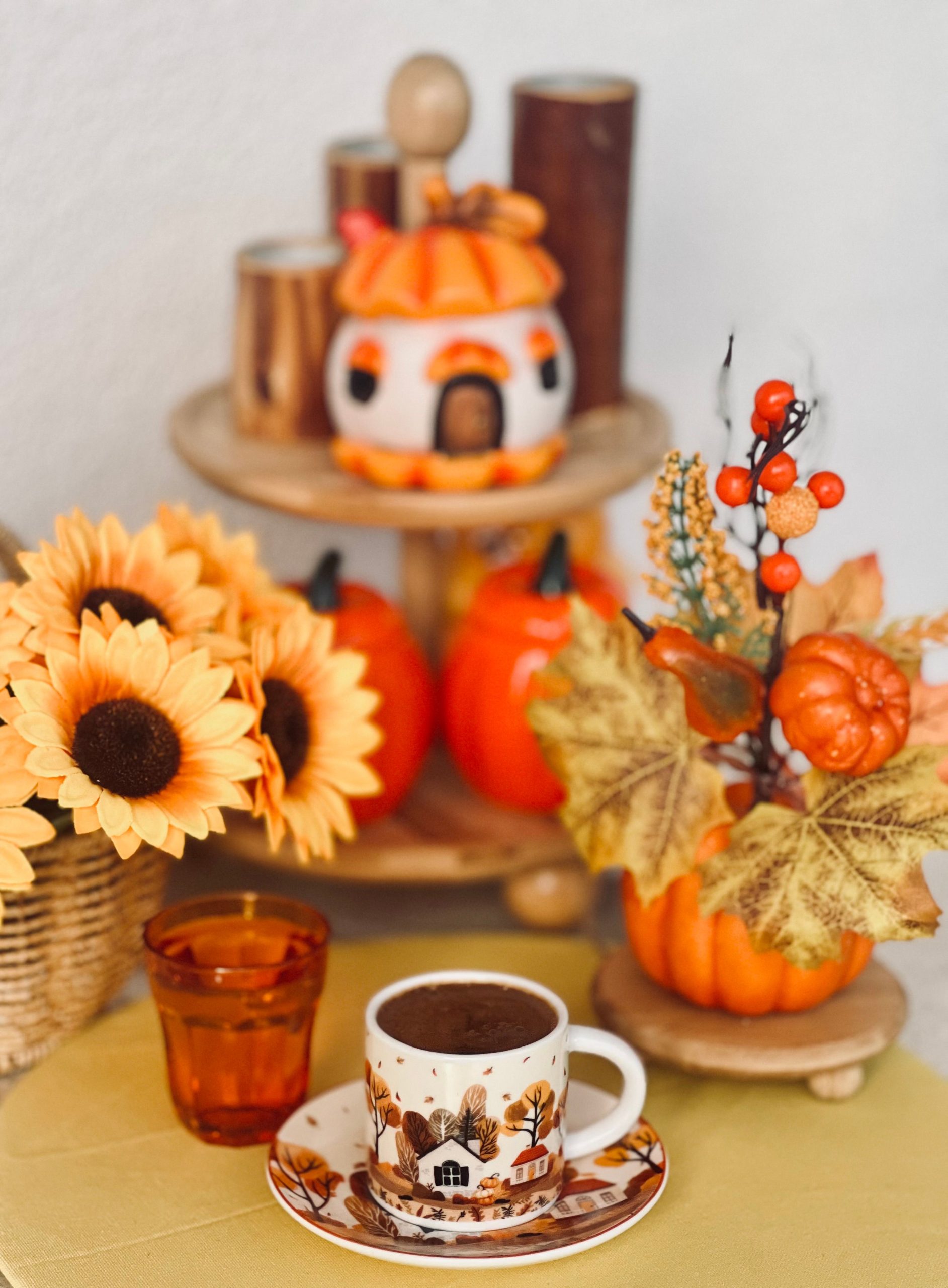 Cozy autumn scene with coffee, sunflowers, pumpkins, and fall decor.