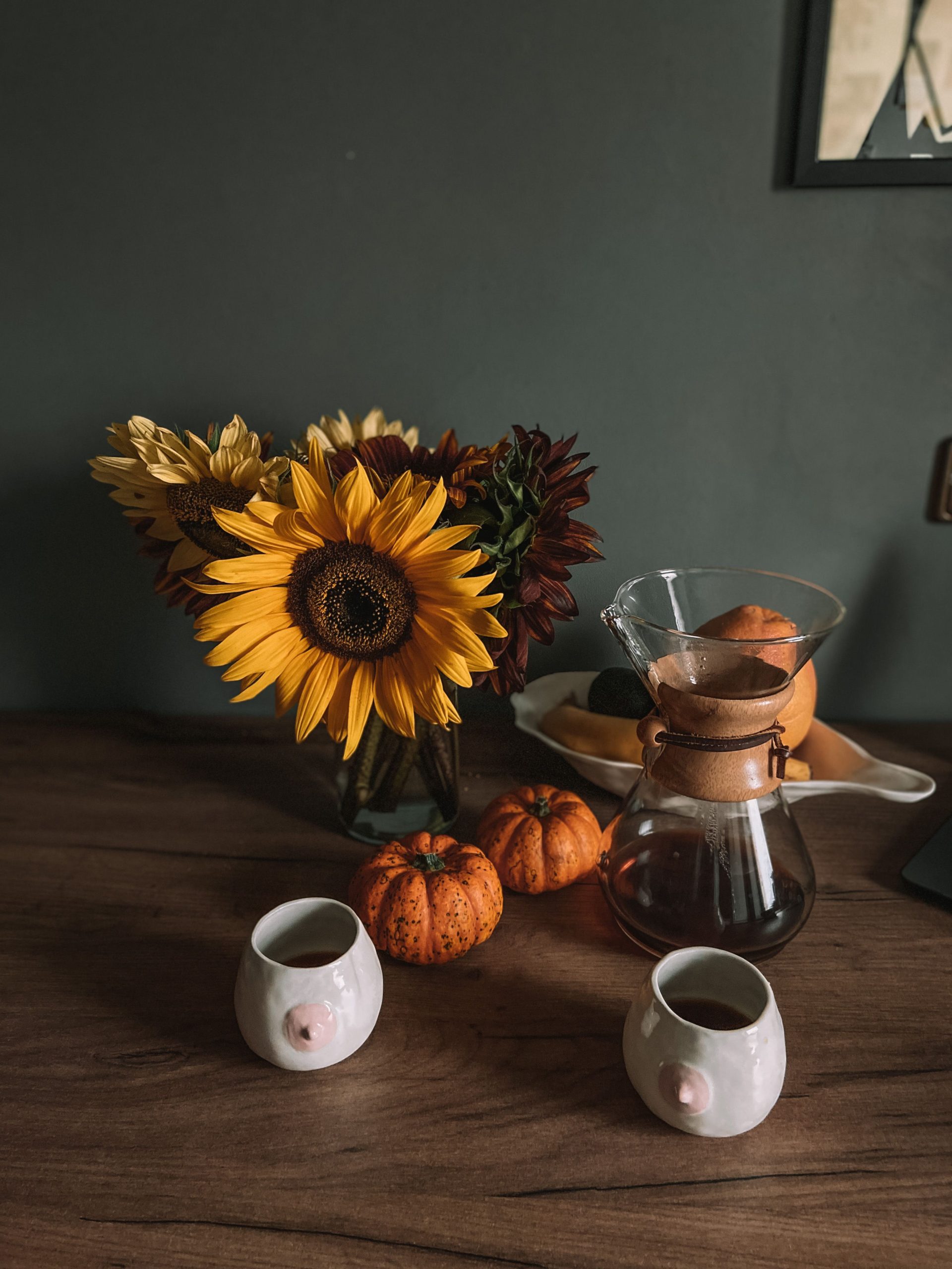 Cozy autumn still life with sunflowers, mini pumpkins, and a coffee setup on a wooden table.