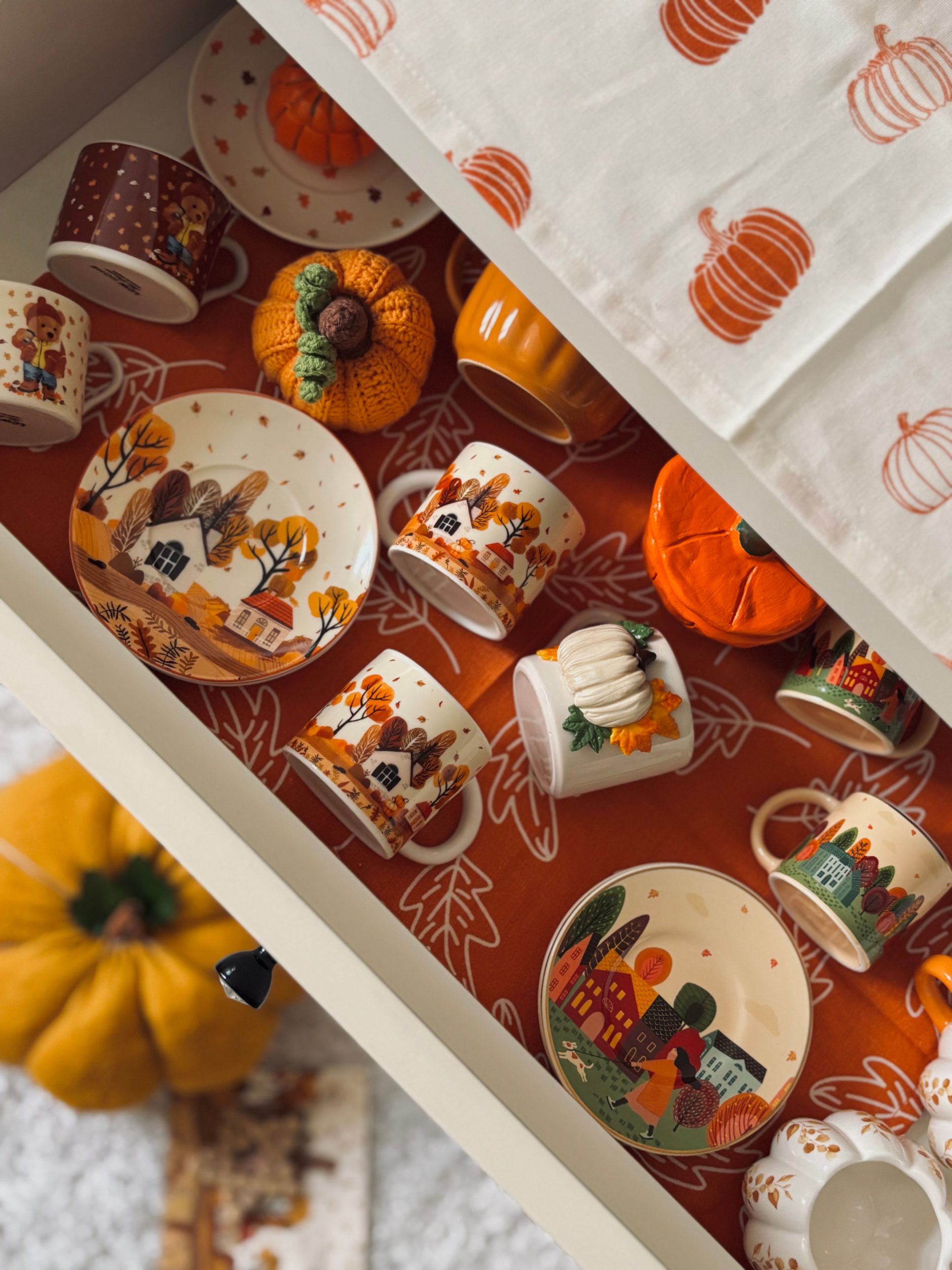 Cozy autumn tableware and pumpkin decor in an organized drawer layout.