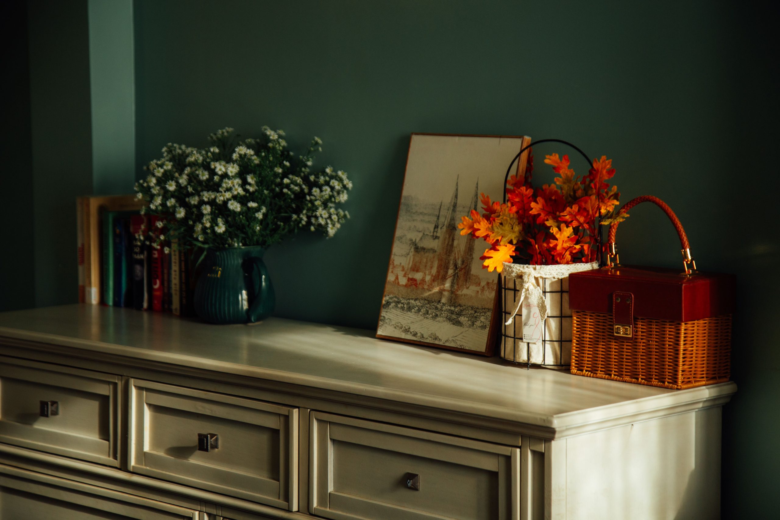 Cozy dresser with floral decor and artwork in warm autumn colors.