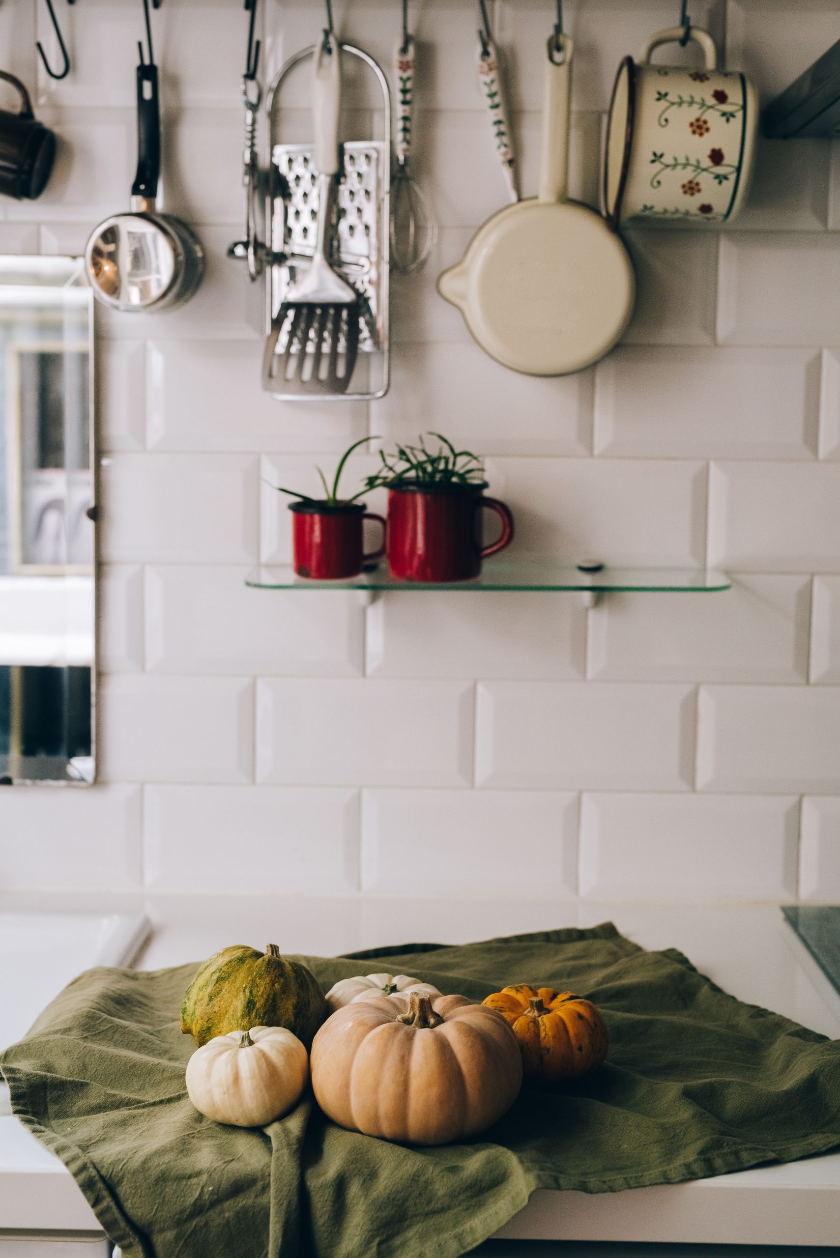 Cozy kitchen scene with assorted pumpkins and decorative mugs, embodying autumn spirit.