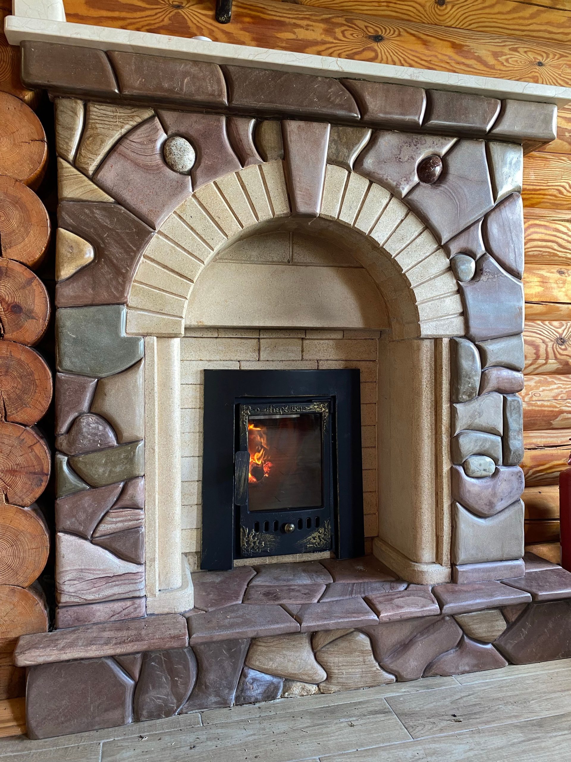 Cozy stone fireplace in a log cabin with a warm fire glowing inside.